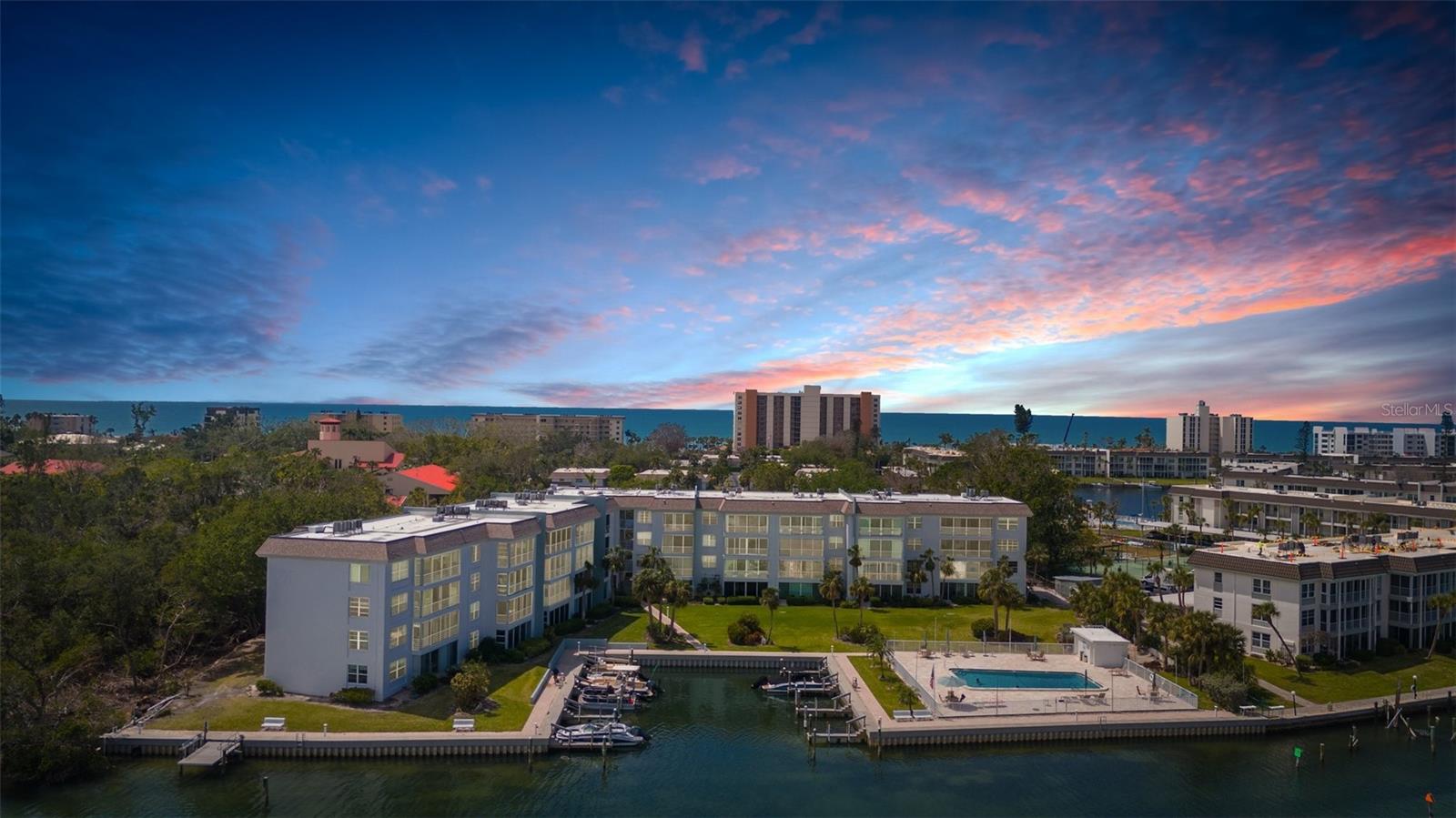 Waterfront condo with Sarasota Bay views!
Perfectly positioned along Sarasota Bay on **Longboat Key** and just steps from the turquoise waters of the **Gulf of Mexico**, this exceptional community offers the ultimate coastal lifestyle in an unbeatable location.  Current owners have never had water intrusion from any hurricanes.
This spacious ground-floor corner residence features an expansive open-concept layout designed to comfortably accommodate up to six guests. The beautifully remodeled kitchen showcases stainless steel appliances, a brand-new range, granite countertops, stone backsplash, recessed lighting, and solid wood cabinetry — blending modern style with everyday functionality.

A charming nook provides the perfect space for additional sleeping accommodations or a cozy retreat to enjoy serene bay views. Impact-rated sliding glass doors open seamlessly to the outdoors and are complemented by brand-new Shade Store cellular window treatments. Relax while taking in peaceful water and pool views from the comfort of your living space.

The spacious primary bedroom features custom cellular shades with top and bottom openings to maximize natural light and views, along with a walk-in closet complete with built-ins. The ensuite bath has been thoughtfully updated with a newer vanity and a brand-new shower remodel (2025), offering a fresh, modern feel.

Furnishings are optional and tastefully curated with designer touches, making this property move-in or rental ready.
Exceptional Community Amenities - Residents enjoy a truly unique waterfront lifestyle: Two heated pools, Marina and clubhouse, Available boat slips for rent, Fish-cleaning station, Kayak storage with electric launch, BBQ grilling areas, Car wash station, Lighted assigned carport parking, Elevator access, Private storage unit (3rd floor), Laundry facility (2nd floor), Exclusive deeded beach access on Longboat Key, featuring a pavilion, storage lockers, indoor showers, and restrooms.

Enjoy watching dolphins and manatees from the bayfront grounds, spend your days fishing or kayaking, or relax on the sugar-sand beaches just across the street. The community is also in the planning stages of adding a brand-new state-of-the-art fitness center.

Shopping and dining are just minutes away at the renowned **St. Armands Circle**.

Experience the best of both worlds — Gulf-front beach days and tranquil bayfront evenings. This is coastal living at its finest.