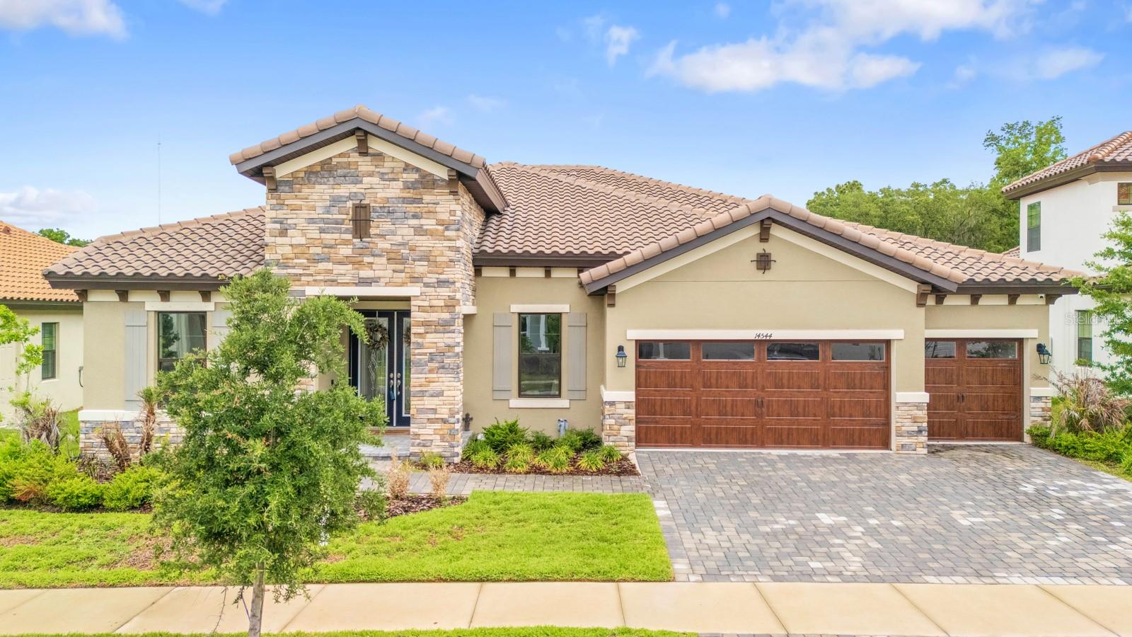 Welcome to the resort-style Hinton Hawkstone community, where this stunning 2023 executive home is move-in ready, with no rear neighbors. This spacious 4-bedroom, 3-bathroom home also includes a private office and a large bonus room, providing flexibility for everyday living or entertaining. From the curb, the home stands out with its tile roof, elegant archways, and pavered driveway leading to a 3-car garage. Inside, you’re greeted by a formal living area and a dedicated office before stepping into the open-concept great room, designed for both comfort and functionality. Throughout the home, you’ll find carefully selected upgrades, cohesive color tones, and stylish finishes that truly shine in person. The primary suite offers a private retreat with a generous walk-in closet and a spa-inspired bathroom featuring dual granite vanities, a soaking tub, and a walk-in shower. The split-bedroom layout provides added privacy, while the versatile bonus room, currently used as a fitness and play space, can easily be converted into a media room, game room, or additional living area, with direct access to the backyard. Additional features include ample storage, an indoor laundry room, and a covered patio that’s pre-wired and plumbed for an outdoor kitchen ideal for creating your perfect outdoor entertaining space. Enjoy the peaceful, tree-lined backyard with no rear neighbors for added privacy. Smart home features such as a security system, whole-home speaker system, and smart thermostat add convenience and modern appeal. Residents of Hinton Hawkstone enjoy access to resort-style amenities, including a lagoon pool with splash pad, lap pool, pickleball courts, playground, dog park, and more, all conveniently located near top-rated Lithia schools.