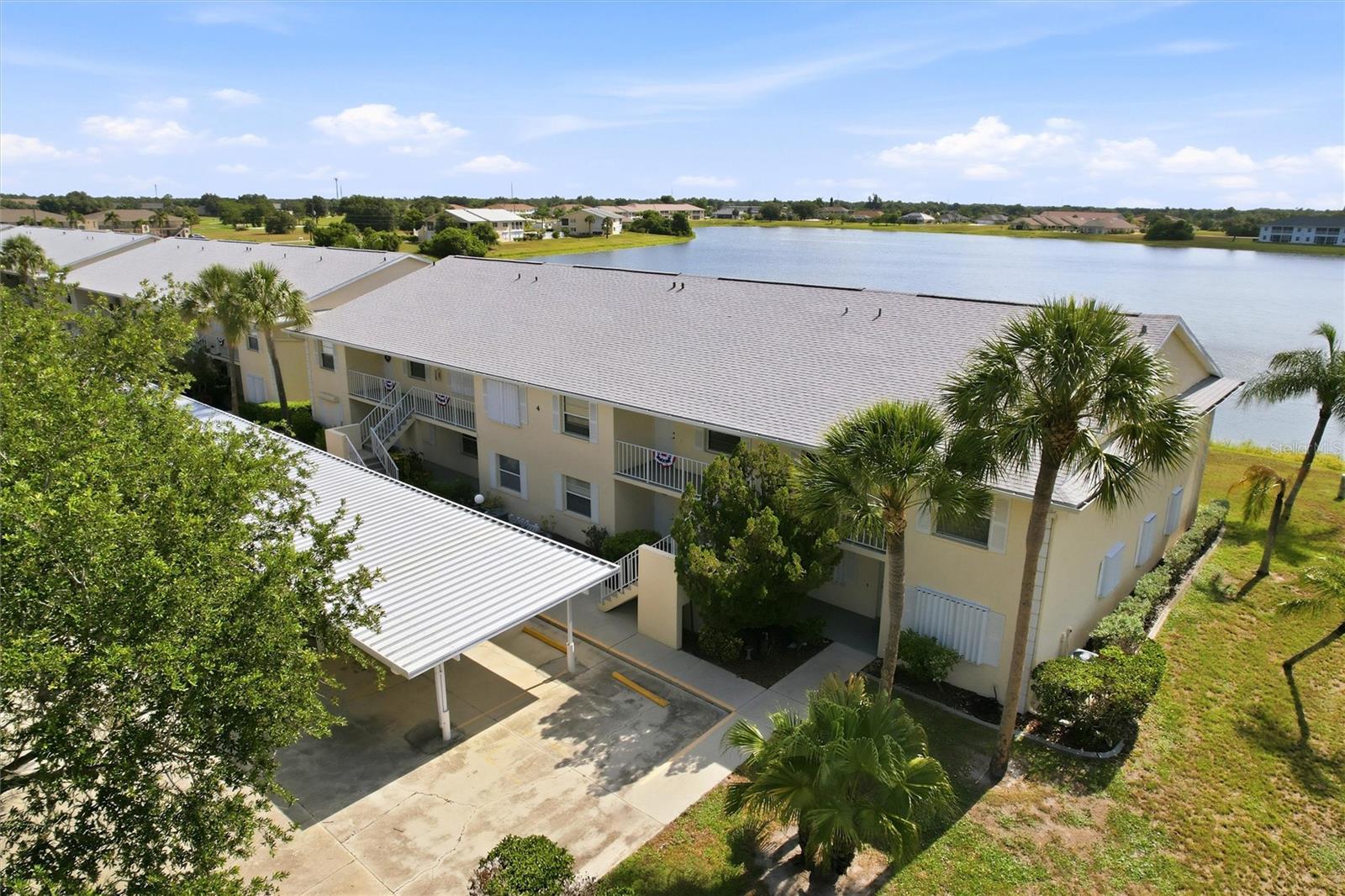 TURNKEY READY!  Enjoy breathtaking lake views from this light-filled second-floor corner condo located in the highly desirable, deed-restricted community of Regency at Deep Creek. This nicely maintained 3-bedroom, 2-bath residence offers spectacular water views from the kitchen, great room, lanai, and spacious primary suite. The thoughtfully designed open floor plan features a split-bedroom layout, creating both comfort and privacy. High, vaulted ceilings, planter shelving and tile flooring throughout enhance the bright and airy feel of the home. The kitchen is both stylish and functional, with white cabinetry, a pantry closet, double sink, and breakfast bar that flows seamlessly into the dining area and great room—perfect for everyday living and entertaining. The spacious primary suite offers private access to the lanai, where you can relax and take in serene lake views. It also features a large walk-in closet and an ensuite bathroom with an oversized walk-in shower. Two additional bedrooms provide plenty of space for family or guests, and the guest bathroom includes a tub/shower combination. The screened lanai offers the perfect place to unwind while enjoying the peaceful waterfront setting. The home also includes an inside laundry room for added convenience. This unit comes with a covered parking space, along with additional guest parking. Residents of Regency enjoy access to a screened, heated community pool and a well-maintained, welcoming environment. Ideally located just minutes from golf courses, shopping, dining, entertainment, and I-75, this home is also a short drive to waterfront parks, fishing piers, and medical facilities. This move-in-ready condo offers the perfect combination of comfort, style, and location—an exceptional opportunity to enjoy Florida living at its best. **PLEASE ENJOY THE 3D INTERACTIVE VIRTUAL TOUR ASSOCIATED WITH THIS LISTING**