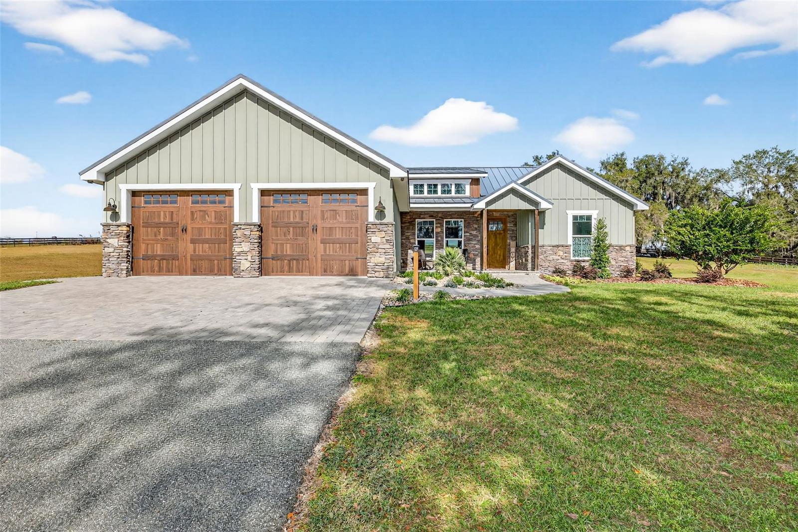 Built in 2023, this thoughtfully designed 3-bedroom, 2.5-bath residence sitting on 5 acres blends modern farmhouse style with exceptional construction quality and timeless finishes. Wrapped in durable Hardy Board siding and built with 2×6 framing, the home is topped with a premium 26-gauge standing-seam metal roof featuring no exposed fasteners, a high-temperature fully adhered underlayment, spray foam insulation beneath the roof, and R-19 insulation in the walls—delivering superior efficiency, durability, and peace of mind.Inside, the home is filled with natural light from PGT high-impact insulated windows and anchored by floating engineered hardwood floors throughout. All doors are 8-foot knotty alder, adding warmth, scale, and architectural presence to every room.The heart of the home is the beautifully appointed kitchen, showcasing custom knotty alder wood cabinetry, KitchenAid stainless steel appliances, a striking custom copper-stamped farmhouse sink, and a coordinating custom copper hood vent. The oversized island and open layout flow seamlessly into the dining and living areas—ideal for both everyday living and entertaining.The living room showcases vaulted ceilings, rich wood trim, and a sleek modern fireplace—creating a space that feels both inviting and refined. Sliding glass doors open to an expansive covered porch, ideal for entertaining, grilling, or simply unwinding. The primary suite is a true retreat, offering generous space, serene views, and thoughtful design throughout. Floating engineered hardwood flooring continues into the bedroom, complemented by warm wood trim, crown molding, and recessed lighting and a modern ceiling fan adds architectural interest, while large windows invite in natural light and peaceful outdoor views.The spa-inspired primary en-suite is nothing short of stunning. Anchored by a freestanding soaking tub with a matte black floor-mounted filler, the bath is finished with full-height porcelain wall tiles that create a dramatic, resort-level feel. The oversized walk-in shower features dual shower heads, multiple body sprays, and a handheld wand, along with a built-in niche and pebble stone flooring for both texture and comfort.A custom vanity with a stone countertop, designer lighting, and rich wood accents provides ample storage and style, while the cohesive blend of natural materials and modern fixtures delivers a luxurious yet calming atmosphere. This primary suite was designed for relaxation, privacy, and everyday indulgence—offering a true owner’s sanctuary.The property is fully fenced, offering privacy, security, and flexibility for a variety of uses. Adding to the appeal is a charming she-shed featuring a welcoming front porch, PGT insulated windows, a mini-split A/C system, and a private bathroom—ideal for a home office, studio, gym, or guest retreat. A 30-amp RV hookup provides added convenience for travelers or visitors.The impressive 50×40 barn offers exceptional versatility and comfort, equipped with PGT insulated windows, three mini-split A/C units, a full kitchen, and a half bath with washer and dryer hookups. The barn also includes a 50-amp RV hookup, making it perfect for extended stays, hobbies, entertaining, or multi-use living and workspace needs.