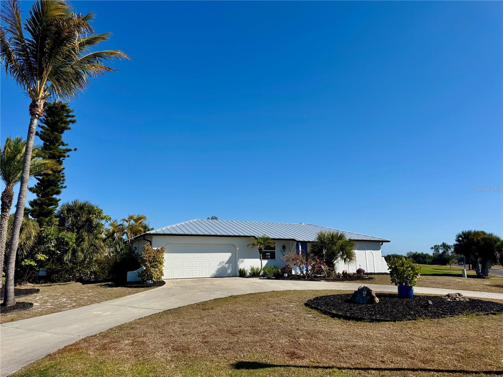 ATTENTION GOLFERS + BOATERS! Positioned on an ELEVATED CORNER LOT in Rotonda West, this property captures SWEEPING GOLF COURSE VIEWS of The Hills Golf Course while placing you in the center of it all. A NEW 2023 METAL ROOF adds lasting value and peace of mind, but it’s the setting that truly sets this home apart. Caddy corner to ROTONDA GOLF & COUNTRY CLUB and THE HILLS RESTAURANT, your tee time or dinner reservation is literally a hop, jump and a skip away! Directly across the street, OAKLAND HILLS MARINA AND COMMUNITY BOAT RAMP provide access to approximately 25 MILES OF NAVIGABLE CANALS, dockage and benches on the Rotonda River — ideal for cruising, kayaking, or casting a line at sunset. An expansive circular drive provides generous on-site parking, and with additional open PARKING DIRECTLY ACROSS THE STREET so hosting friends, family gatherings, or larger get-togethers is refreshingly easy (or book the clubhouse next door!) Inside, the home is light, bright, and coastal in feel with wood-look plank tile and an open floor plan designed for easy living. A spacious living room anchors the front of the home, welcoming in natural light and marina views. At the center, an updated galley kitchen features STAINLESS STEEL APPLIANCES, SOLID WOOD CABINETRY, and a breakfast bar that overlooks the oversized dining room — a flexible space that could easily transition into an additional sitting area, den, or media lounge depending on your needs. The split bedroom layout offers privacy for owners and guests alike. The primary suite is generously sized with a walk-in closet, ensuite bath, and direct access to the lanai — ideal for morning coffee without an audience. The second bedroom is equally spacious, complete with a mirrored closet and an ensuite bath that functions as a guest bath in a smart Jack-and-Jill design. The large garage provides built-in storage and houses the laundry area, keeping things practical and organized. Out back, the SCREENED LANAI becomes your front-row seat to the course. Quiet, peaceful mornings when play is light. Lively, entertaining views during peak hours. All of it framed by open green space that adds distance between you and the next home — something you’ll appreciate more and more over time. While this location provides an unmatched lifestyle right outside your door, this area also provides immediate access to other greater area taverns, parks, beaches and so much more! Call today to explore it all!