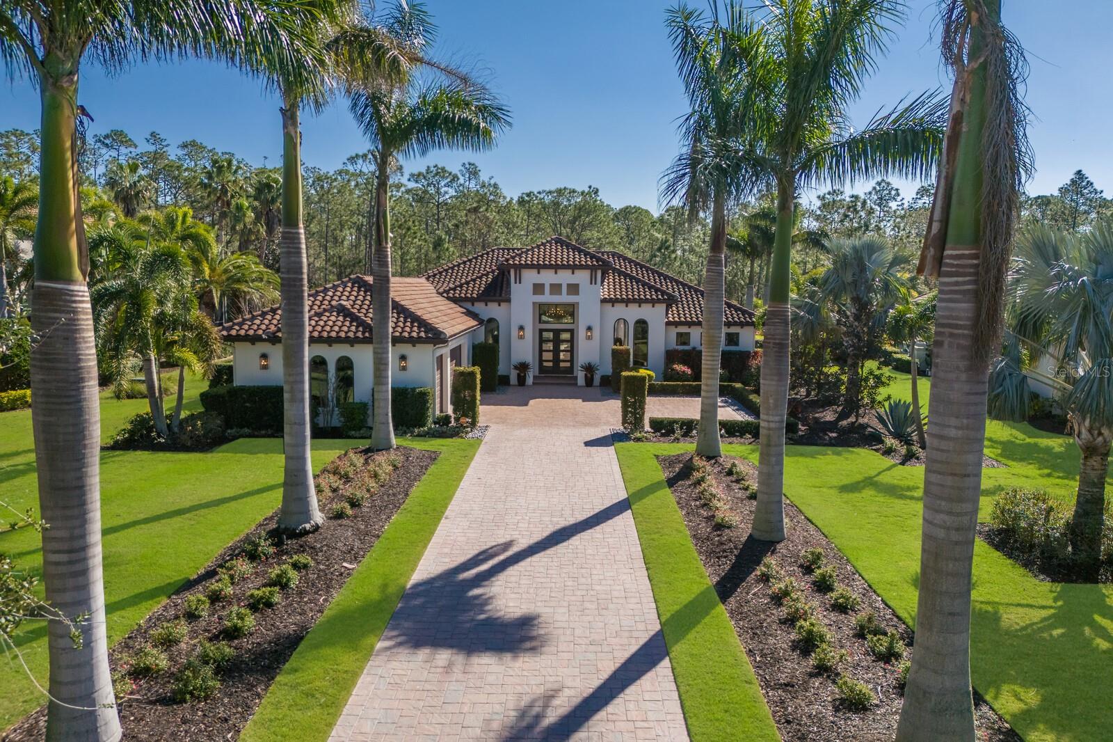 Make your way down the long paver drive lined by dramatically uplit Royal Palms and meticulously manicured grounds that stretch across more than three-quarters of an acre. 19424 Ganton Avenue stands in the distance, a masterpiece of design and luxury, framed by the towering presence of Florida pines and ancient 200-year-old oaks in the backdrop. This stunning contemporary home is filled with the finest finishes yet has comfort and family in mind. The grand room makes a statement from the moment you enter with soaring ceilings, professionally styled interiors, custom trim work, built-ins, crown mouldings, a linear fireplace, and bespoke lighting. 10-foot-high by 22-foot-wide pocket sliding doors offer an unobstructed view of the nature outside. Impact glass protects the entire home from the outside world, but within, the ambiance is filled with tranquility and refinement. The gorgeous kitchen makes a statement in this residence boasting gas Thermador appliances, fine custom cabinetry with soft-close drawers and pull-out shelves, dramatic quartz countertops, and a massive island which serves as a gathering spot for family and friends. Glass-front cabinets illuminate from within to showcase your family's most important pieces and a 10-foot-tall glass-enclosed dual-sided wine display, is a showpiece that reveals your carefully selected vintages. Throughout the house, every detail is a testament to the homeowners' desire for perfection.  The primary suite is a luxurious retreat with access to the lanai, two custom-organized walk-in closets, a spacious marble vanity, crown molding, a large pass through shower, and a free-standing tub. The office features tall arched windows, high ceilings, and glass doors. Each of the two guest bedrooms have generous closet space and en-suite bathrooms. The bonus room, just off the great room, opens directly to the expansive covered lanai, where the true luxury of this home comes to life. The travertine deck stays cool in the late afternoon sun and surrounds a salt water pool and spa. The substantial summer kitchen—equipped with a granite-topped island, Blaze professional grill, Marvel outdoor fridge, prep sink, and a massive vent hood—welcomes outdoor dining and entertaining. It is in the tranquility of the fully fenced backyard, however, where the true drama unfolds. The serenity of the surroundings, the beauty of the perfectly curated landscape, sculpted hedges, and the majesty of the unspoiled 60+ acre forest all combined to create a rare kind of peace that is not easily obtained.  Bordering Lakewood Ranch, residents of the Concession enjoy all of the activity in and around the area but enjoy no CDDs, more spacious estate lots, a high security guard gate, and optional membership to the Concession Golf and Country Club. The Concession was home to the 2021 PGA Tour World Golf Championship and the 2023 PGA World Champions Cup, is the selected host of the 2026-2028 Senior PGA Chamionships, and is known as one of the most prestigious golf communities in the country .