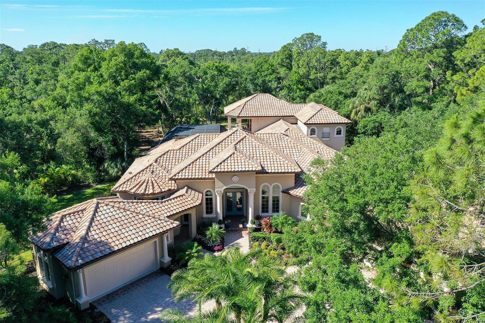 Step into your dream home nestled amongst majestic oaks and nature. This stunning property, set on a beautifully forested 3.27-acre home site within The Forest at Hi Hat Ranch, offers a unique blend of luxury and tranquility. No two homes are alike within this gated community of acreage custom estate homes.

Spanning 5752 square feet, this custom-built masterpiece by John Cannon Homes boasts 4 bedrooms ,4 bathrooms, 2-Powder Baths, Study, Game room and Theater providing ample space for both relaxation and entertainment. Upon entering, you'll be greeted by an atmosphere of elegance and sophistication, where modern design seamlessly merges with timeless charm.

Natural light floods the spacious living area through large windows, creating a warm and inviting ambiance. The gourmet kitchen is a chef's delight, equipped with top-of-the-line stainless steel appliances, sleek granite countertops, and custom cabinetry. A temperature-controlled wine room is seamlessly integrated near the formal dining room to provide easy access to your most prized vintages.

Retreat to the luxurious master suite and indulge in the spa-like ensuite bathroom, complete with a soaking tub, dual vanities, sauna and a spacious walk-in shower. All guest bedrooms and second floor are updated with custom wood flooring and feature ensuite bathrooms.

Step outside to your private oasis, where outdoor living meets luxury. The expansive backyard features a covered patio with a full outdoor kitchen and firepit overlooking the pool and spa provide for endless entertainment possibilities. The game room equipped with entertainment options like a pool table, pinball machine, and shuffleboard create the perfect spot for unwinding. For the movie buff a private theater is located on the second floor and is perfect for family movie night!

Upgrades abound throughout the home, including a whole-home reverse osmosis water system, security cameras, hurricane impact windows, and more. Conveniently located in Sarasota, this home offers easy access to shopping, dining, entertainment, and the pristine beaches of Siesta Key and is located within an A rated school district.

Don't miss the opportunity to own a piece of paradise in Sarasota. Schedule your showing today and experience luxury living at its finest!
