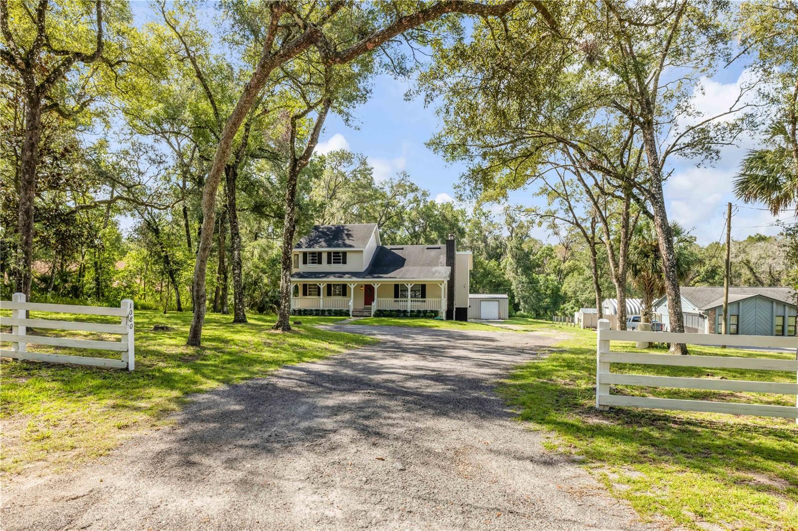 Tucked away on a private, dead-end dirt road, this inviting property offers freedom, space, and privacy—with NO HOA. Set on an expansive lot, there’s room to live, work, and play while enjoying the peace and quiet of country-style living. Start your mornings on the charming front porch, coffee in hand while sitting in your rocking chair, as birds and local wildlife provide a serene backdrop. Step inside and feel instantly at home in the warm, welcoming interior, where an open living room and cozy fireplace create the perfect gathering space. The main level features guest bedrooms and a large office/den conveniently located off the living area—ideal for working from home or accommodating guests. Upstairs, retreat to the private primary suite, complete with its own balcony—a perfect spot to unwind with a morning coffee or evening cocktail. A large attic space off the primary bedroom offers excellent additional storage. The kitchen, located at the back of the home, provides plenty of room for family meals while overlooking the backyard. Just outside, a secluded deck invites outdoor entertainment, with stairs leading down to the rear of the home where you’ll find a one-car-attached garage and laundry area. At the back of the property sits the true showstopper—an oversized workshop/garage built with Red Iron Steel (2001), featuring roll-up doors and electricity. With ample space for boats, golf carts, antique cars, or hobbies, this structure offers endless possibilities. Additional highlights include: Two A/C units (downstairs unit 2023 | upstairs approximately 10 years old) Roof replaced in 2018 /Hot water heater 2023 / Septic and well. Plenty of room to add a pool. Recent 4-point inspection completed. This one-of-a-kind property combines comfort, functionality, and freedom—a rare find with space to grow and enjoy your lifestyle without restrictions. Call today to schedule your private tour!