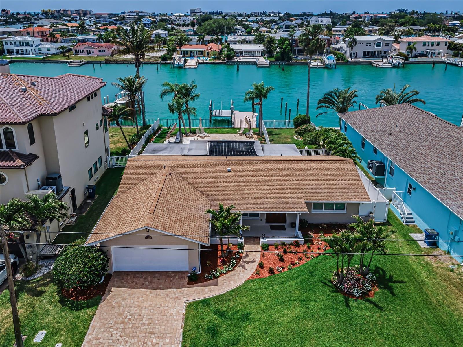 Set on a deep-water canal in the sought after Isle of Capri neighborhood in Treasure Island, this beautifully renovated waterfront residence offers a refined take on coastal living, just a short walk or golf cart ride to the beach and the Treasure Island boardwalk. With 75 feet of seawall along Boca Ciega Bay, the home enjoys a natural and effortless connection to its coastal setting. Freshly redesigned landscaping and a pavered driveway create an inviting first impression, setting the tone for what awaits inside. A welcoming entry framed by glass paneled wood doors opens to a light filled interior where travertine flooring flows throughout. The main living area is expansive and inviting, with impact rated windows that draw in natural light and frame calming water views. The layout transitions effortlessly to the covered outdoor space, creating a true indoor-outdoor lifestyle. The kitchen blends timeless design with function, featuring white shaker cabinetry, stainless steel appliances, a farmhouse sink, and quartz countertops that extend to the backsplash creating a clean, cohesive look, while counter height seating offers a natural gathering space. The primary suite offers a private retreat with two closets including a walk-in with custom closet systems, and a beautifully appointed bath with floor to ceiling tile and a walk-in shower. A Florida room extends off the suite, offering a flexible space ideal for a home office, sitting room, or quiet escape, complete with its own mini split system and peaceful water views. A split floor plan provides privacy with two spacious guest bedrooms, each with built in closet systems. The guest bath features a sleek walk-in shower and serves as a convenient pool bath. Outdoors, the property transforms into a private oasis. The newly installed outdoor kitchen is thoughtfully positioned for easy hosting, complete with a gas grill, sink, refrigerator, and ample storage, while a separate sunshade system enhances comfort over additional seating area. A fenced lawn offers space for pets or play. The 2020 treks dock is equipped with water, electric, and a 15,000-pound lift, offering quick and easy access to the Gulf from a deep-water canal. Additional features include impact rated windows and doors, brand new electric shades on every window, smart home integration, updated ductwork, sound system, new irrigation, and a two-car garage with built in cabinetry and utility sink. Residents can enjoy the short stroll to Rosselli Park which features newly updated pickleball courts, shuffleboard, a playground, dog park, gazebo, and baseball field, all while being moments from the sand, dining, and vibrant coastal lifestyle that defines Treasure Island. This is a home that seamlessly brings together thoughtful design, modern upgrades, and the everyday ease of waterfront living. Buyer to verify all dimensions.