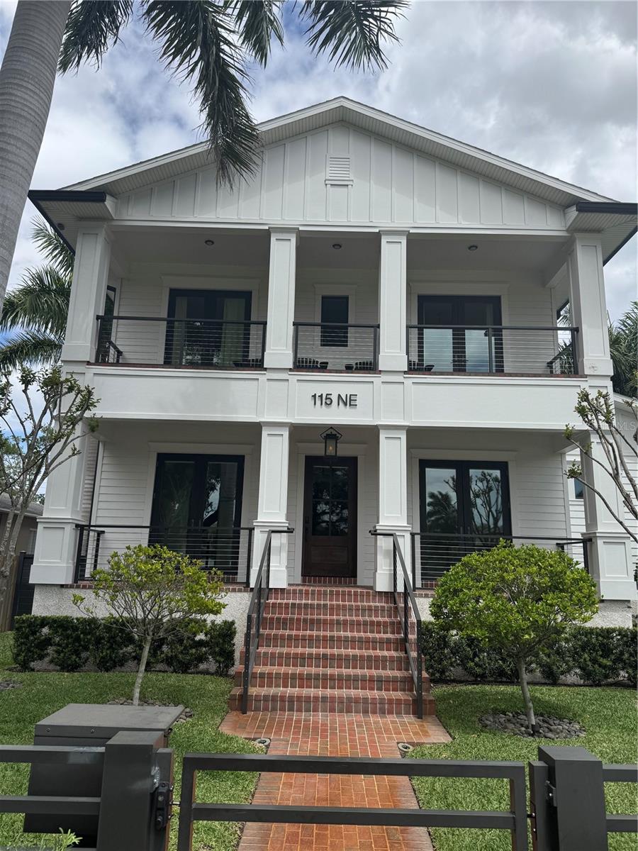 Welcome to a one-of-a-kind masterpiece located at 115 27th Ave NE in St. Petersburg, nestled in the highly coveted Historic Old Northeast. Built in 2020 and perfectly positioned on an oversized 60x137 lot along a charming brick-lined street with sidewalks, this custom residence offers over 3,000 square feet of elevated living with three bedrooms, five bathrooms, and exceptional attention to detail throughout. From the moment you arrive, the grand brick entrance and lush, meticulously maintained landscaping set the tone. Spectacular front porches on both levels provide the perfect vantage point to enjoy this picturesque street, while custom metal fencing and a Wi-Fi-controlled gated driveway with a new gate motor offer privacy and modern convenience. Constructed with solid block and wrapped in Hardie board siding and trim, the home features hurricane-impact windows throughout and pocket sliding glass doors that seamlessly blend indoor and outdoor living. Inside, you’ll find nickel gap wall paneling, pecky cypress ceiling and range hood accents, and French oak hardwood flooring that adds warmth and elegance throughout. Designed with entertaining in mind, the gourmet kitchen is a showstopper—complete with Sub-Zero and Wolf appliances, a built-in wine cooler, oversized walk-in pantry, and custom bench seating for casual dining. The formal dining room connects beautifully through a wet bar and pantry, creating a seamless flow for gatherings both large and intimate. The main-level primary suite is a true retreat, featuring a spectacular walk-in closet with a window that fills the space with natural light. Just beyond, a private outdoor sitting area offers a peaceful escape—perfect for morning coffee or quiet reading. Each of the three bedrooms includes its own en suite bath and custom wood closets, with access to private outdoor spaces. A flexible den area features built-in bunk beds, ideal for guests or creative use, while a dedicated office can easily serve as a fourth bedroom if desired. Upstairs, transom lighting enhances the bright and airy feel, while the laundry room stands out with blue cabinetry and abundant natural light, making even everyday tasks feel elevated. Step outside to a spectacular outdoor living space designed for year-round enjoyment. A covered lanai with a built-in wood-burning fireplace overlooks the gorgeous pool and spa, creating the ultimate setting for relaxation or entertaining. Enhanced by a new pool pump and surrounded by lush landscaping, this backyard retreat is further elevated by computer-controlled garden lighting and a computer-controlled irrigation system, offering beauty and efficiency at the touch of a button. Additional modern upgrades include Wi-Fi-controlled door locks, whole-home Wi-Fi extenders for seamless connectivity, and smart integration throughout. The oversized two-car garage is a standout feature, complete with air conditioning, Gladiator wall paneling, a finished floor, and ceiling height suitable for a car lift. Further highlights include marble bathroom finishes, plantation shutters, spray foam insulation, copper gutters and chimney cap, coquina shell banding along the exterior, and two natural gas tankless water heaters for optimal efficiency and comfort. Perfectly located in one of St. Petersburg’s most desirable neighborhoods, this property offers luxury, innovation, and timeless design—all in an unbeatable setting. This is more than a home—it’s a lifestyle. Take a look inside today!