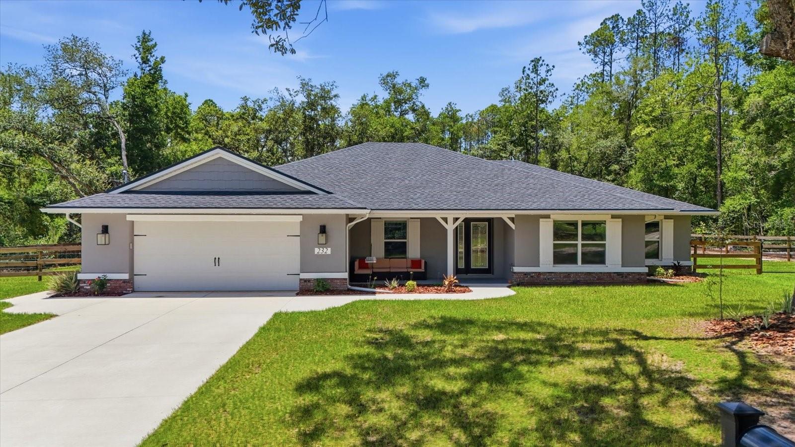 Charming Ranch Retreat! Tucked back on a spacious, tree-lined homesite, this beautifully updated single-story home offers the perfect blend of modern comfort. A long concrete driveway winds through mature oaks and pines to a stately gray home with a welcoming covered front porch, complete with craftsman-style wood columns and a cozy seating area, the perfect spot for morning coffee. Step inside to an open-concept living room featuring a soaring tray ceiling, wood-look luxury vinyl plank flooring, and a ceiling fan for year-round comfort. French doors lead out to a covered porch overlooking the fenced backyard, seamlessly blending indoor and outdoor living. The kitchen is a showstopper, with crisp white upper cabinetry paired with rich blue lower cabinets, sleek quartz countertops, stainless steel appliances, and a large center island with bar seating and a farmhouse-style sink. A sunny dinette area with a stylish chandelier sits just off the kitchen, offering the perfect casual dining space with backyard views. The primary suite is a true retreat, boasting another tray ceiling, oversized windows that flood the room with natural light, and plenty of space for a king-size bedroom set. Conveniently located in the growing community of Citrus Springs, you'll enjoy the perfect balance of peaceful living and everyday convenience. Historic downtown Dunnellon and Rainbow Springs State Park are just 15 minutes away, while Lecanto is approximately 15 minutes away for shopping, dining, and major medical facilities. In about 20 minutes, you'll reach Crystal River, renowned for boating, fishing, waterfront dining, and the world-famous manatees. Surrounded by some of Florida's most beautiful natural springs, you'll have endless opportunities to swim, snorkel, kayak, tube, and explore the crystal-clear waters that make the Nature Coast so special.