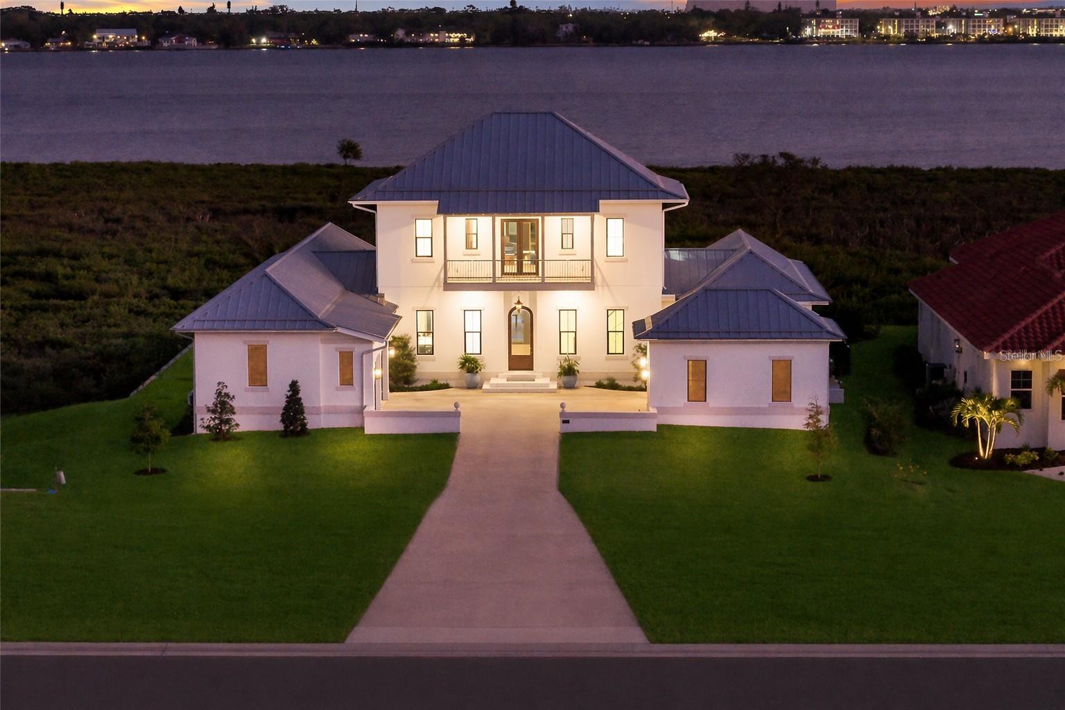 A TRULY EXCEPTIONAL NEW CUSTOM BUILT WATERFRONT ESTATE ON THE MANATEE RIVER WITHIN THE PRESTIGIOUS GATED ENCLAVE OF WATER'S EDGE AT SANCTUARY COVE! Uncompromising craftsmanship and sweeping panoramic water views create an extraordinary  residence. Designed with inspiration from the Coastal Living Idea House by Cooper Johnson Smith Architects, this remarkable home offers a rare blend of refined craftsmanship, resort-style outdoor living, and direct boating access, creating an unparalleled Florida lifestyle defined by elegance, comfort, and effortless indoor-outdoor living.
Perfectly positioned to capture sweeping water views from the front, rear, and side elevations, the home includes a 35-foot private boat slip with a 10,000 lb lift, complete with water and power. Built with lasting quality in mind, this home features a standing seam metal roof, half-round galvalume gutters, a closed attic system and spray foam insulation throughout the second floor. Interiors are finished with level 5 smooth drywall, engineered oak hardwood flooring throughout, and extensive custom millwork and casework. Architectural details include custom door surrounds, transoms in the living room, cove molding, and LED-accented coastal molding in the family room and kitchen. Ceiling heights impress with 12-foot ceilings along with vaulted ceilings in the kitchen, family room, porch, and primary suite.
The chef’s kitchen is designed for both function and entertaining, featuring high end cabinetry, a custom chateau style range hood, granite countertops with warm neutral tones, a one-piece granite island with seating for five, banquette seating, an 8-burner gas double oven range, warming drawer, and under-cabinet and cove lighting. The kitchen flows seamlessly into the family room and screened porch, enhancing the home’s open-concept design.
A well-appointed laundry and utility space offers quartzite countertops, a full pantry, laundry sink with cabinetry, hanging space, and additional linen storage. The primary suite is a private sanctuary with a vaulted ceiling, motorized blackout shades and a private terrace with full river views. The spa-inspired bath features marble finishes, double sinks, basketweave tile detailing, marble wainscoting, and a multi-head shower system with rainfall, waterfall, and body sprays, along with thermostatic controls and a heated towel rack. The suite also connects to a private courtyard with a fountain and outdoor shower.
Outdoor living is equally impressive with a heated and cooling saltwater pool and spa. The exterior showcases a herringbone brick driveway, golf cart parking, and distinctive copper gas lanterns at the front entry and screened porch.
Modern efficiency and technology include a whole-house natural gas generator, two tankless gas water heaters and smart LED lighting.
This extraordinary residence offers a rare opportunity to own a meticulously designed waterfront home that seamlessly blends architectural excellence, luxury finishes, and premier boating access in one of the area’s most desirable coastal communities.  This home offers convenient access to the 365 acre Emerson Point preserve, the beaches of Anna Maria Island, local restaurants and two nearby airports. Embrace the beauty of Florida waterfront living, where boating, sunset views and coastal relaxation are part of everyday life.
