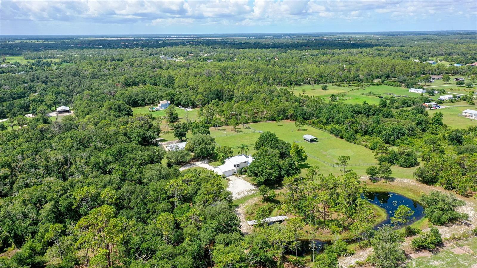 Discover the ultimate horse property, whether you are an avid rider looking to keep your horses at home, dreaming of running your own boarding facility, or envisioning new creative uses for a versatile barn. This 9.41-acre estate offers all the essential elements: flat, cleared, and spacious land with fencing and cross-fencing, creating a safe and inviting environment for both family and animals. Nestled within this peaceful setting is a custom-built 4-bedroom, 3-bath, 2-story home that blends comfort with nature. A brand-new (2025) metal roof ensures peace of mind. The main floor boasts a chef-inspired kitchen with center island, stainless appliances, abundant counter space, and storage. Cozy up by the wood-burning fireplace on chilly evenings or enjoy views of the pool and hot tub. The owner’s suite on the first floor is filled with natural light and features a deluxe en-suite with jetted tub, walk-in shower, and dual sinks, plus a generous walk-in closet. A second bedroom on the main level provides flexibility for guests or a private office. Upstairs, a spacious loft doubles as a game or movie room, along with two large bedrooms and a full bath. Outdoor living shines here with an enclosed pool deck and covered entertaining spaces. The oversized detached barn features 8 stalls, tack room, wash area, storage room, excellent ventilation, and water and electricity to all stalls. Five separate pastures, two with direct stall paddocks, and an additional shelter building with water sources ensure comfort and convenience for your horses. Numerous nearby riding trails enhance the equestrian lifestyle. The barn’s concrete flooring makes this property especially versatile. As it stands, it’s a premier equestrian setup with income potential: Full Boarding @ $1,100/month, Partial Boarding @ $650/month, Self-Boarding @ $450/month. Alternatively, the barn offers exciting and unique possibilities as a BARNDOMINIUM (Barndos) conversion—transforming into a full residential living space, adding a second-level apartment, or remodeling into a classic car storage / garage (see attached floor plans). With acreage supporting two homes, this property allows flexible living and working solutions. Picture mornings as the sun rises over your land, relaxing by the stocked pond, or fishing from the rebuilt bridge that leads to your private island, complete with bonfire space for memorable gatherings. Just outside Panther Ridge, you’ll enjoy the best of both worlds—close to shopping, schools, and medical facilities, yet far enough to savor privacy and tranquility with no HOA fees or Deed Restrictions. Just 15 minutes to I-75, it’s an ideal location for your equestrian lifestyle. Do not miss out—saddle up and make this dream property your own!