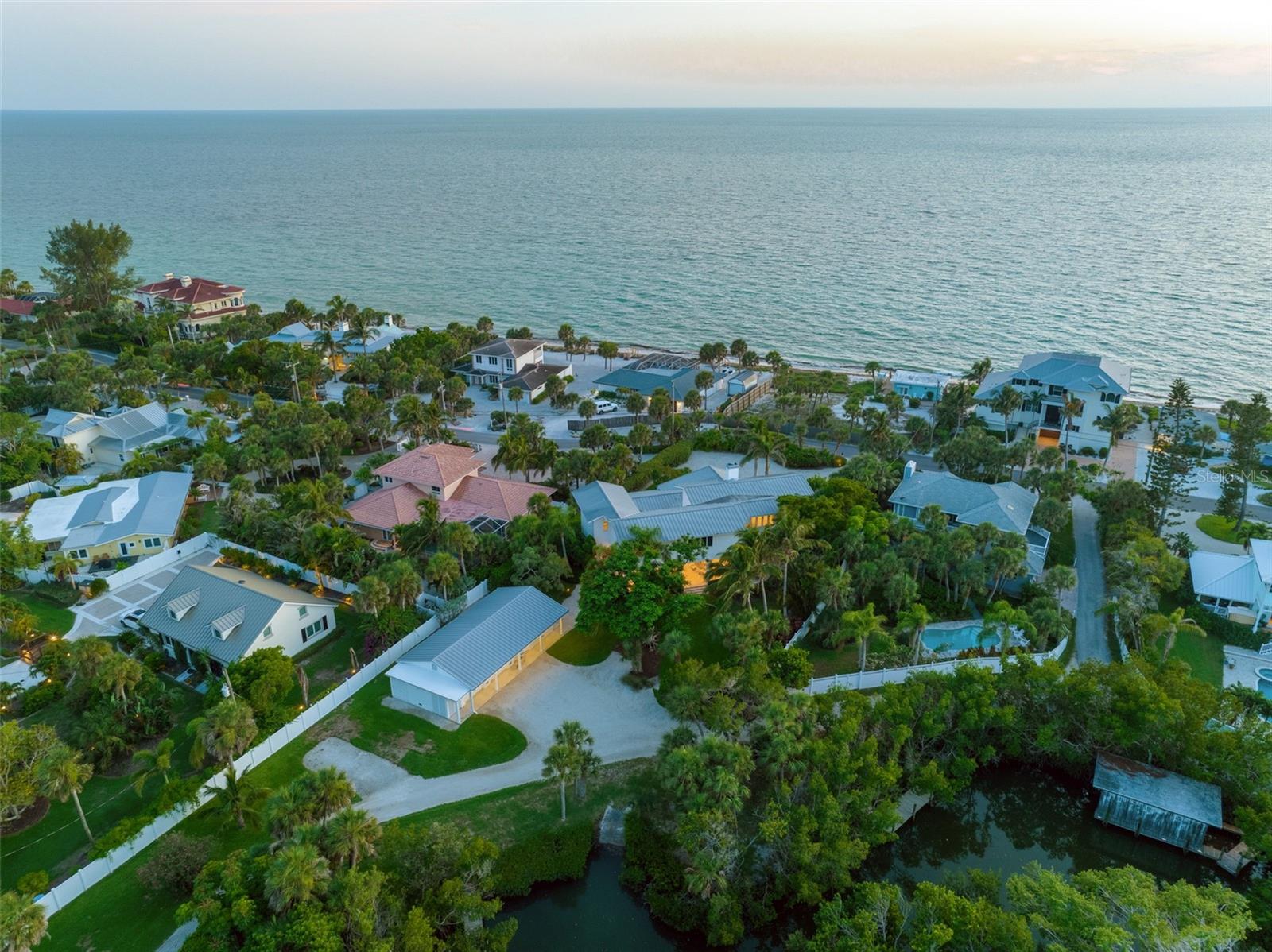 Welcome to your Island retreat on Casey Key! This exquisite beach house exudes classic charm and offers a truly idyllic setting. Nestled on nearly an acre of land, this hidden gem provides the perfect blend of privacy and proximity to a private deeded beach easement, where miles of pristine shoreline await your exploration. Located on Cutlass Bayou, the home's bayside waterfrontage is nestled on a protected basin. With easy boating access to the Intracoastal Waterway, you'll appreciate the convenience of a private boat launch and dock. The mean high water depth of 4 feet ensures smooth sailing on your aquatic adventures. Embrace the essence of outdoor living with the exquisite outdoor kitchen, dining, and living areas. Revel in the classic Florida lifestyle as you dine al fresco. Plans for a new pool and spa are underway, and are currently in the permitting process.Step inside the home, where limestone floors and an abundance of natural light create an inviting ambiance. The flexible floor plan allows for versatile use, with a home office and plenty of room for guests.  The kitchen is a culinary dream, featuring top-of-the-line Decor, Bosch, and Sub-Zero appliances. Spacious family and living rooms, complemented by a beautiful fireplace, offer ample room for gathering and entertaining. A separate dining room provides an elegant setting for formal meals. Ascend to the master bedroom upstairs and wake up to Gulf views. Witness stunning sunsets from the comfort of your own private retreat. Three additional generously sized bedrooms, two full baths complete the second floor. For the avid hobbyist or water sports enthusiast, the three-car garage and workshop provide the perfect space to tinker, store boating gear, and house water sports toys. Located near the north bridge, accessing and departing the island is a breeze, offering added convenience. Positioned between Sarasota and Venice, you'll enjoy easy access to a wealth of shopping and dining options. Discover why Casey Key, an eight-mile-long barrier island, is hailed as the jewel of the Gulf Coast and holds a special place in the hearts of its fortunate residents.