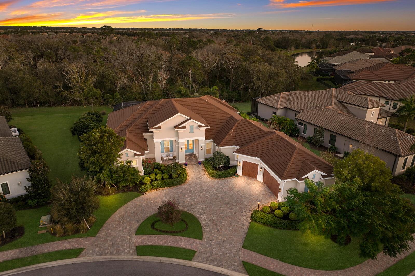 Exquisite Lee Wetherington masterpiece nestled among mature landscaping and tranquil preserve views in the prestigious gated community of Eaglescliffe in Country Club East. Situated on a premier lot with almost 1/2 acre of Southeastern exposure located in a cul-de-sac, this stately home is the perfect blend of sophistication and refinement. Beautiful curb appeal welcomes you with a circular paver driveway leading to an oversized 3+car garage with plenty of room for 3 cars plus golf cart. Tastefully designed with a timeless palette and accentuated with gleaming hardwood floors, 11’ & 12’ ceilings with elegant architectural detailing, hardwood beams and handcrafted millwork this expansive 3,802 sq ft home offers 3 bedroom suites, 4 full Baths, plus a 122 sq ft air conditioned “Florida Basement”. IMPACT GLASS for storm protection throughout the entire home. Picturesque views from the panoramic clear view screen entice you as you enter this luxurious home. The oversized covered paver lanai boasts over 2300 sqft of exceptional resort-style outdoor living. Offering multiple seating areas, Summer kitchen with an Alfresco natural gas grill with vented hood, natural gas fire pit, and sparkling gas heated salt water pool and spa, transitions effortlessly into the main living areas with disappearing sliding glass doors, allowing for seamless indoor and outdoor living. The open concept floor plan showcases the chef inspired kitchen with state of the art appliances, Sub Zero refrigerator, Wolf gas range, Wolf microwave, and Bosch dishwasher. Custom cabinetry with soft close drawers and pullout trays is accented with a traditional beadboard on the counter height island, custom stacked hood, Quartzite countertops and a mosaic tile backsplash. A large built-in hidden pantry allows for ample storage and functionality. Built and designed with entertaining in mind, this home features a glass enclosed wine room with 116 bottle dual temperature controlled wine refrigerators, custom cabinetry with quartzite countertops and bar sink. Retire to the owners suite, a tranquil sanctuary with a private entrance to the lanai designed wiith two generous walk-in closets with custom closet systems, one of which is a 20’x8’ “Hollywood” closet with refrigerator and built-in ironing station. The luxurious bath has a large walk- in shower with 2 rain heads, custom cabinets with dual sinks, a sit down makeup vanity and a glorious soaking tub. This home offers two spacious guest bedrooms, each with their own en suite, perfect for hosting family or guests. For those that work from home, a double french door entry leads to a private study with views of the pool and separate lanai entrance. Additional upgrades include; 2 zone A/C heat pump system with WiFi thermostat, 400 amp electric service, pre wired for emergency generator, tankless instant hot water heater, water softener, central vacuum, whole house security system and Ring doorbell. Country Club East, a private gated community, offers its residents amenities including fitness center, 2 clubhouses, and 3 community pools. Opportunites are available to become members of Lakewood Ranch Golf and Country Club, 2 clubhouses for dining, tennis, pickleball, pools and fitness. Country Club East Lakewood Ranch is conveniently located to exceptional shopping, dining, and A rated schools. Don’t miss this rare opportunity to live in exceptional luxury.