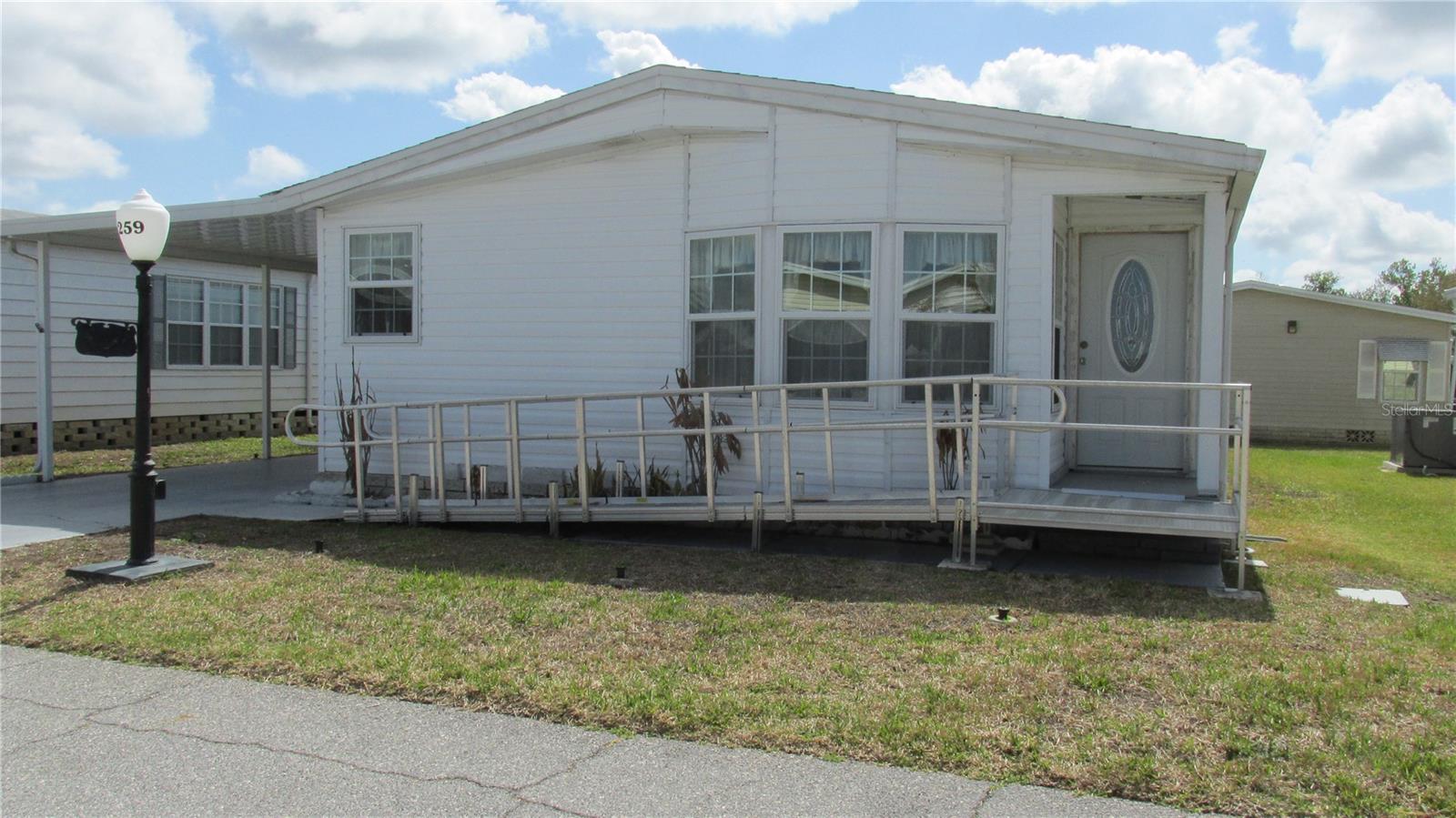 This nice 1990 Fleetwood home measures 1196 SF of living space. Kitchen is small but very functional. This home is unfurnished and awaits you for your personal touches. Two bedrooms & two full bathrooms. Master bath is shower only with the guest bathroom having a shower/tub combination. Living room and dining area combined makes for easy entertaining. There is a wheelchair ramp that can be left or easily removed. A private lanai area for relaxing is attached to laundry area/storage.  No walking outside. This home is located in a very active 55+ community with many activities and amenities. The 18-hole executive golf course is small but challenging. Located on Lake Henry, offering boating and fishing.
