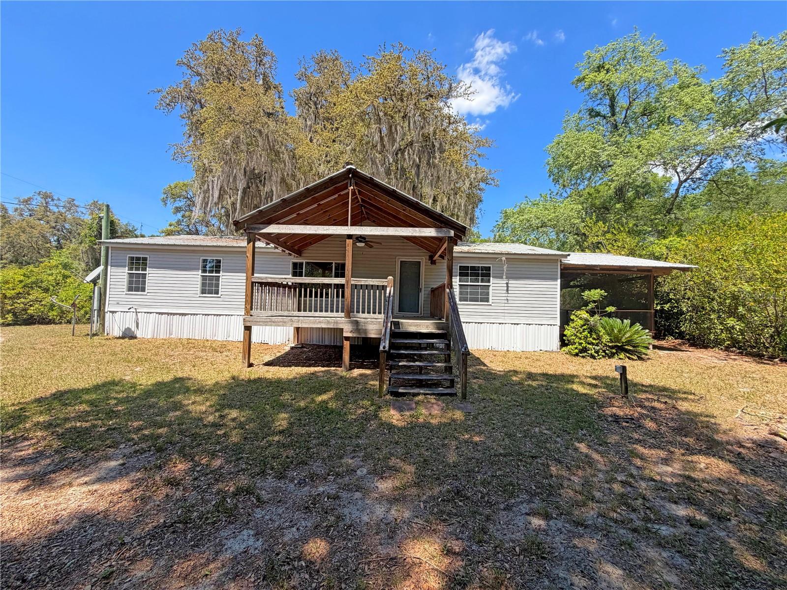 Opportunity meets location with this 3-bedroom, 2-bath home in the Lak-A-Wana Gardens community. NO HOA! This property offers a functional layout and multiple outdoor living spaces designed to enjoy Florida living. The home features a metal roof, a large covered front porch, peek-a-boo views of Lak-A-Wana, and a spacious screened side porch off one of the bedrooms-perfect for relaxing mornings or evening unwinding. The .30-acre fenced yard provides room for pets, gardening, or outdoor entertaining. A standout feature is the large garage, ideal for storage or a workshop, along with a carport positioned in front for additional covered parking. The garage does need a new roof. Enjoy deeded access to Lak-A-Wana, lakefront park with a dock and boat ramp, perfect for fishing, boating, and soaking in the peaceful, uncrowded setting. The area is loved for its small-town charm, natural surroundings, and central convenience. With easy access to Gainesville, Palatka, and Ocala, plus nearby trails, lakes and outdoor recreation, it's an ideal location for those wanting a quieter lifestyle without being far from town. A unique opportunity to own a property with lake access, usable space, and room to add your personal touch.