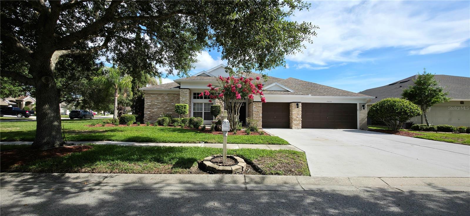 Welcome to 25638 Ferdinand Court, Wesley Chapel, FL 33544 - in the highly sought after golf course community of Lexington Oaks in Pasco County Florida. A stunning two-story residence that redefines what Florida living can look like. From the moment you arrive, the natural stacked stone facade, mature tropical landscaping, soaring double entry doors, and three-car garage signal something truly special. Step inside to discover a grand formal foyer with wainscoting panel molding and crown molding, flowing into an open-concept great room with rich dark hardwood plank flooring, formal dining room with coffered archway and wainscoting on three walls, and a chef's kitchen featuring granite countertops, a center island, stainless steel appliances, and direct access to the lanai. The covered screened lanai is nothing short of extraordinary, spanning nearly 500 square feet with THREE sliding glass door connections from the kitchen that disappear behind the wall once opened. It also connects to a spacious family room, and primary suite, creating seamless indoor-outdoor Florida living at its finest. The primary suite offers a private 3 sliding doors that also lead to the lanai, a newly added frameless glass walk-in shower and elegant marble, a soaking garden tub, dual vanity, and walk-in closet. Three additional bedrooms all feature dark flooring and crown molding. The crown jewel? A massive upstairs bonus room with wet bar, pre-wired surround sound, with panoramic backyard views of the lake that's perfect as a media room, game room, or home theater. Outside, you'll enjoy the partially fenced pool-ready backyard with mature queen palms, lush lawn, and pond view is your blank canvas for the ultimate Florida oasis. This is Wesley Chapel luxury real estate at its absolute finest, and it will not last. The upates are contuning as the home will be ready to show soon enough.