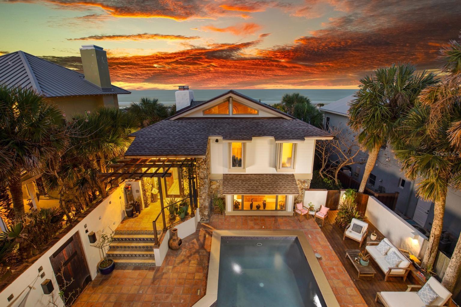 Experience coastal luxury at “Pura Vida,” a Costa Rican-inspired retreat in the prestigious North Beach area, where privacy, craftsmanship, and timeless elegance converge. An exceptional offering with a fully independent guest residence, where both the primary home and guest quarters stand on their own in scale and design yet combine to create a truly expansive oceanfront estate. This fully reimagined 4-bedroom, 5-bath estate offers direct beach access and commanding, unobstructed views of the Atlantic—delivering a truly bespoke coastal retreat. Designed for both refined entertaining and serene everyday living, the property showcases expansive outdoor environments, including a grand oceanfront deck and a secluded walled courtyard with a resort-style pool enveloped in lush tropical landscaping. Recent main house renovations include a brand-new roof, micro cement flooring, primary suite laundry, and fully painted exterior. Inside the main residence is a refined blend of bamboo and travertine flooring throughout, revealing a sophisticated, thoughtfully curated layout with dual living areas, ideal for hosting or multi-generational living. The oceanfront primary suite is a sanctuary of its own, featuring a private sitting area, fireplace, and an expansive dressing room designed for elevated comfort. The chef’s kitchen is a statement in both form and function, appointed with custom bamboo cabinetry, and a suite of premium appliances by Sub-Zero, Wolf, Bosch, and Fisher & Paykel, complemented by a generous walk-in pantry. Additional distinctions include a richly appointed family room with custom built-ins and fireplace, a detached guest house offering private suites. A 3-car garage with integrated storage and secondary laundry enhances everyday convenience. This is a rare offering—an exceptionally private, turnkey oceanfront estate defined by quality, design, and exclusivity, set within one of New Smyrna Beach’s most coveted coastal enclaves just moments from fine dining, boutique shopping, and vibrant local culture. All information recorded in the MLS is intended to be accurate but cannot be guaranteed.