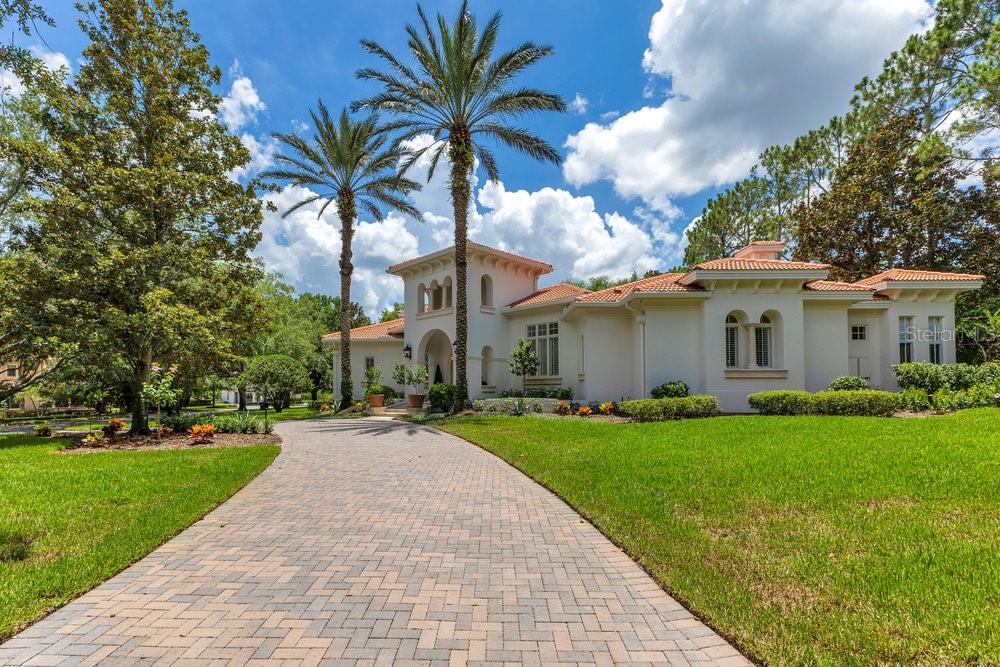 A Masterpiece of Design in the Heart of Isleworth – 6186 Louise Cove Drive. Stunning, design magazine-worthy residence nestled behind the exclusive 24-hour guard-gated community of Isleworth, one of Central Florida’s most prestigious neighborhoods. This exquisite estate sits on a spacious 0.75-acre corner lot, surrounded by mature landscaping and a stately circular driveway that sets the tone for the luxury that awaits inside. No expense was spared in the recent $1 million designer remodel, which brought in California-based interior designers to source the finest materials from around the globe. Step through grand arched solid wood double doors into a soaring foyer where 16-foot ceilings and imported white French oak floors flow throughout the home. Walls were meticulously finished to level 5 smoothness a testament to the craftsmanship and attention to detail throughout. Designed for both entertaining and everyday living, the open-concept family room centers around a venetian plaster fireplace and effortlessly flows into a show-stopping double island kitchen. Imported German cabinetry is complemented by one piece quartzite slabs and backsplash, while high-end appliances include a 6-burner Wolf range with double ovens, a paneled Thermador refrigerator & freezer, venetian plastered hood, beverage fridge, and under counter microwave are all seamlessly integrated for a refined look. Retreat to the expansive primary suite, where comfort meets luxury. Enjoy access to a private study, Florida room, and a spa-inspired bathroom featuring a stand-alone soaking tub, oversized glass shower with handmade 4x4 Moroccan tile, French brass fixtures, and custom lighting.  Primary suite also features a spacious walk-in closet offering custom built-ins, providing both elegance and functionality. The home’s Santorini-inspired full pool bath is a work of art in itself, with artisan stucco finishes adorning every surface. Each secondary bedroom is an en-suite, with marble or handcrafted tile finishes and ample closet space. Outdoors, your private fenced backyard oasis features a heated pool & spa, covered summer kitchen, and expansive lanai, perfect for enjoying Florida’s year-round sunshine. Additional highlights include a whole-house generator, tankless water heaters, four AC units, and a designer laundry room with imported German cabinetry. Live minutes from world-class attractions, dining, and elite schools, yet enjoy the serenity and security of one of the region’s most sought-after enclaves.