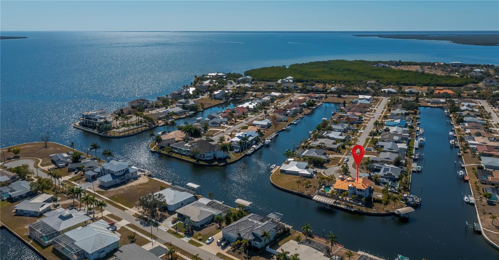 Experience the PINNACLE OF WATERFRONT LUXURY at 290 Tait Terrace, an EXQUISITE EXECUTIVE RESIDENCE set on a ILLUSTRIOUS 260 FT TIP LOT offering panoramic harbor vistas and quick SAILBOAT to the harbor and Gulf. Built with CONCRETE BLOCK TOP TO BOTTOM & ELEVATED at 12FT this custom 2008 4-BEDROOM 4-BATH 3-CAR GARAGE masterpiece accompanies refined open-concept living, graced by soaring 22-foot ceilings, custom crafted arched wooden front door, exceptional chihuly style glass chandeliers, elegant tray ceilings, stunning marble-like tiled floors and cathedral sunburst windows that flood every room with natural light and invite gentle cross breezes throughout. The open-concept office is a sophisticated serene workspace, thoughtfully designed with crown molding & coastal shiplap accents plus expansive desk areas, bathed in natural light from large windows/ soaring ceiling overlooking the grand foyer and circular driveway. This quiet retreat is perfect for focused work/ study while staying connected to the beauty outside.The den offers a cozy, versatile space for relaxation, reading, or a media lounge, providing additional privacy and comfort with sliders to the outside terrace/ pool w dimensional saltwater views. The oversized family room serves as the heart of the home, featuring a seamless flow to the adjoining spaces, highlighted by expansive glass doors that open to the terrace, creating an ideal setting for both intimate family moments and lively entertaining. Dining is an elegant affair here, whether enjoying a casual meal or hosting grand celebrations distinguished by its exquisite lighting and stunning views, while the adjacent gourmet chef’s kitchen features 2 SPECTACULAR BREAKFAST BARS. 
The gourmet chef’s kitchen is a work of art, showcasing granite countertops, premium stainless steel appliances, crafted wood cabinetry w meticulous attention to detail & perfectly positioned walk in pantry/butler closet.Retreat to the lavish master suite, a sanctuary w breathtaking saltwater views, coffered ceiling, plantation shutters, dual walk-in closets, w private pool & patio access. The spa-inspired ensuite indulges with a soaring 22-foot spa shower featuring resort style rain shower heads and bespoke fixtures, a jetted tub, & dual vanities crafted for luxury and comfort. The thoughtful split floor plan offers 2 generously sized guest suites on the main floor, while an impressive 4th bed Primary suite on the second floor boasts sweeping waterfront views & access to a private European-inspired balcony — the perfect vantage point for serene mornings & breathtaking evenings, complete with an elegant ensuite bathroom.
Outdoor living is an entertainer’s dream with a paver lined heated pool with separate spa, multiple terraces for lounging and dining, and two private docks with 2 covered boat lifts (Fishing Boat & Yacht) for effortless gulf access. Savor spectacular sunsets that paint the sky in vivid hues! Additional highlights include 2026 seawall being installed for full 260 ft, 2024 dual-zone A/C system, 2014 STANDING SEAM 100 YR METAL ROOF, NEW SEAWALL INSTALLED 2026, hurricane window, no HOA, public water/ sewer, & underground utilities — every detail designed for luxurious waterfront living. Ideally located near Port Charlotte Beach, historic Punta Gorda, Sunseeker Resort, vibrant dining, festivals, & the airport. Don’t miss your chance to own this extraordinary waterfront estate. Schedule your private tour today and step into your dream.