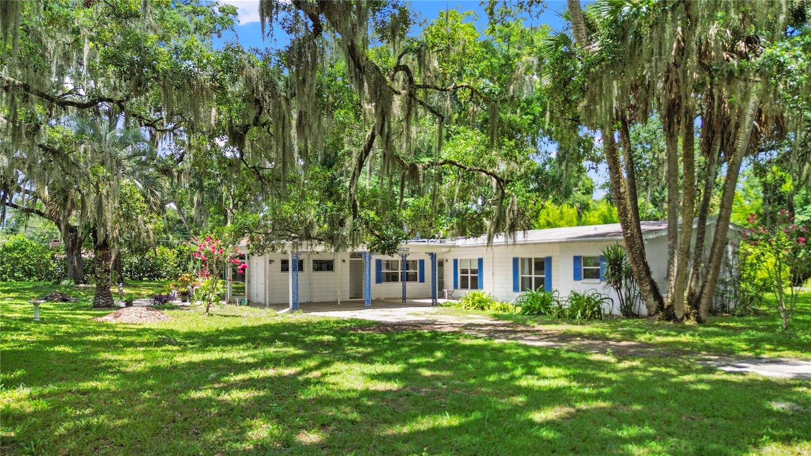 Looking for tranquility and Old Florida Charm? Look no further than 2430 SW 6th Avenue, a quaint mid-century gem boasting an oversized lot and high ceilings with custom wood beams in the highly coveted Lake Louise Subdivision. Tucked down a limerock road in one of Ocala's highest elevation areas- NO HOA/ NO FLOOD ZONE- sits this 3 bedroom/ 3 full bathroom concrete block home. On your drive up, you'll immediately notice the spectacular Oak trees and Azaleas along the property line. The yard is storybook, and also home to 5 Turkeys basking in the backyard. Drive all the way up to the oversized carpet, and step inside to soaring ceilings and a gathering space for your loved-ones. We love the wood burning fireplace found in the family room; plus the Florida room, a second living space, just beyond that. The natural light is abundant as large windows frame views from the kitchen and dining room. While doing dishes, take a peak at the lovely Sunflower garden from the kitchen window. Down the hall, find 2 primary suites, plus a guest bedroom/ office, and the indoor laundry room with full bath including step-in shower. Both primary baths are spacious and offer tub/ shower combos. Updates: HVAC (2024); Propane Gas tank on property which supports the gas water heater down the hall, and the kitchen stove; wooden blinds. Enjoy exterior storage with shelving under the covered porch. Washer/ dryer to convey. *Roof will need replacement for insurance purposes. Make your own cosmetic updates or enjoy the mid-century character as-is. This property is the perfect location to live quietly in County limits, while conveniently located just a few miles from downtown Ocala, shopping, medical facilities, and fun activities. This dreamy property is calling your name!