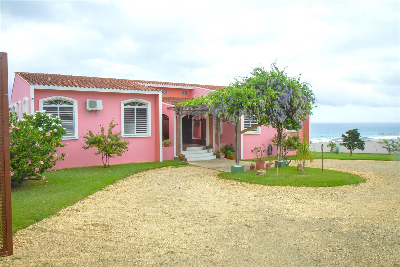 Hilltop Mediterranean style residence in the beautiful ful north-west coast of Jobos ward in Isabela. This unique property of 3,000 sq. m. offers a strategic vantage point with panoramic ocean views. Situated on nearly 1 acre of land, this private oasis, ensures absolute privacy by being strategically located at the end of a street and secured by imposing walls and gates featuring two entrances for exclusive access.
The property opens with a grand driveway, leading to the main residence and a guest house with two- vehicle garage. The guest house boasts a complete kitchen, bathroom, and a balcony with stunning views. The main house is thoughtfully designed, presenting distinct spaces for various functions, including library, living, sitting, and office areas.
The functional heart of the home includes a well-equipped kitchen, dining area, and laundry facilities. The master suite epitomizes comfort, featuring a walk-in closet, master bathroom, and a balcony offering captivating ocean views.
A family area bathed in natural light offer a full kitchen, bathroom, dressing area, and ample space for amenities. A private and independent studio apartment adjacent to the family area provides guests with direct access to the infinity pool and deck areas, fostering a seamless indoor-outdoor experience.
Outdoor amenities es include a pool, sun deck, and gazebo ideal for entertaining and relaxation, giving you an intimate connection to the ocean. In addition, the large green areas, covering 2,000 square meters, offer multiple possibilities for potential enhancement.
This residence exemplifies Caribbean luxury living, representing a unique investment opportunity in a coveted location on the Caribbean coast, delivering a harmonious blend of exclusivity and coastal lifestyle. Elevate your living experience with this exceptional offering.