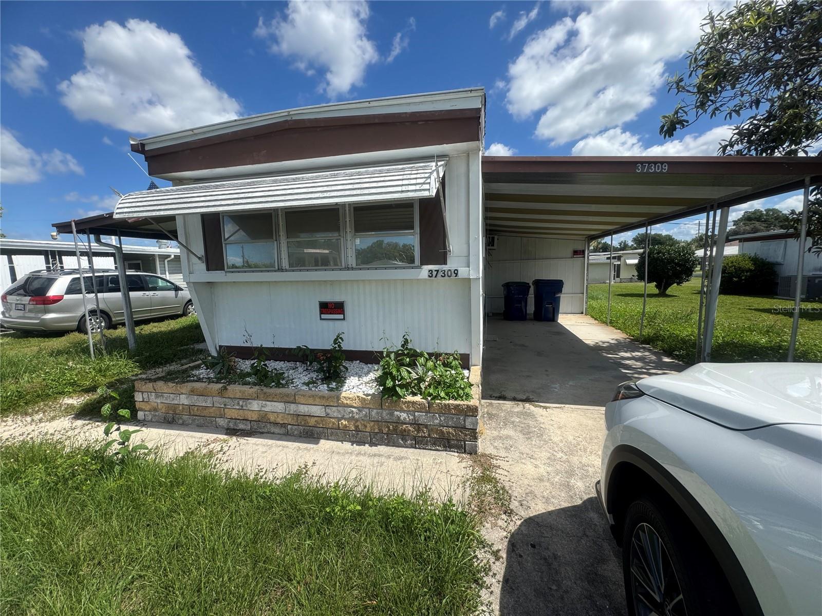 GREAT FIXER UPPER - this 1967 single-wide mobile home with 2 bedrooms, 1 bath, street-level screenroom, metal over roof and 2 sheds for storage has great bones and no leaks in the double roof. There is 744 square feet of living space just waiting to be updated.  The 9'x17" street -level screened porch and the 9'x23" covered carport add extra space for entertaining. This home has great potential.  All it needs is an owner with a vision to bring this trailer back around.  And it's located just blocks off of Pure Water Way (SR 54) close to shopping!  Betmar Acres offers three 9-hole golf courses, two swimming pools, and two hot tubs along with a lot of activities throughout the year for additional fees.  Perfect for full-time living and cost-effective for snow birds! Fixer uppers, please take a look!