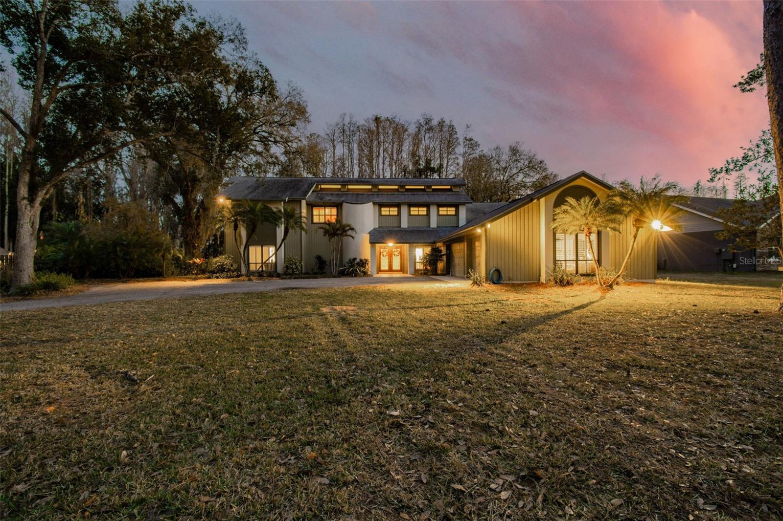 Gracefully positioned along the water and privately set on over 1.14 acres of picturesque grounds, this exceptional lakefront residence offers 5 bedrooms, 3.5 baths, an oversized three car garage, and a resort-style pool. Surrounded by sprawling pine trees and tranquil views, the setting evokes a sense of serenity and retreat rarely found in residential living. Inside, the home is defined by soaring vaulted ceilings, dramatic architectural lines, and abundant natural light, creating a feeling of openness and warmth. Elegant plantation-style shutters throughout add timeless character and refinement. The gourmet kitchen serves as a stunning focal point, beautifully positioned to capture views of the pool, grounds, and lake beyond. Anchored by a spacious center island and enhanced by custom cabinetry, refined lighting, and a beautifully integrated designer range hood, the space blends function and design effortlessly. Overhead and under-cabinet lighting create a warm ambiance, while the premium appliance package includes a dishwasher, new cooktop stove, built-in oven, refrigerator, microwave, wine fridge, and more. A whole house intercom system enhances convenience and connectivity. The family room offers an inviting gathering space centered around a beautiful wood burning fireplace, creating a warm and intimate atmosphere. The primary suite is a true private retreat with direct access to the pool and outdoor living areas. The primary bath offers a spa like experience, featuring dual vanities, a soothing jacuzzi tub, a walk-in shower with dual shower heads, custom cabinetry, beautiful lighting, and a private water closet. A remarkable custom closet system and dedicated AC further enhance comfort and luxury. The thoughtful layout includes two Jack and Jill bathrooms connecting secondary bedrooms on both levels, along with a convenient half bath downstairs. Each bathroom features a walk-in shower, blending modern design with everyday ease. An upstairs laundry chute adds additional convenience, while a built-in cigar humidor reflects distinctive custom detail. Outdoors, the property transforms into a private resort style escape. A sparkling pool with cascading spa and integrated hot tub, expansive screened pavilion, outdoor kitchen, BBQ area, and custom bar equipped with a five-keg cooler create an entertainer’s paradise. Commercial-grade cooking features, stainless steel prep areas, and an integrated surround sound speaker system elevate the experience. Sweeping lake views and breathtaking sunsets provide a spectacular backdrop. A private boardwalk leads to the owned dock, offering rare and highly sought-after lake access for kayaking, paddleboarding, gentle boating, and quiet reflection. Recent improvements, enhance peace of mind and overall livability. Newer roof, hot water heater, and iron removing water softener system, enhance both comfort and long term peace of mind. This is more than just a home. It is a lifestyle property defined by privacy, atmosphere, and refined lakefront living. Welcome home...