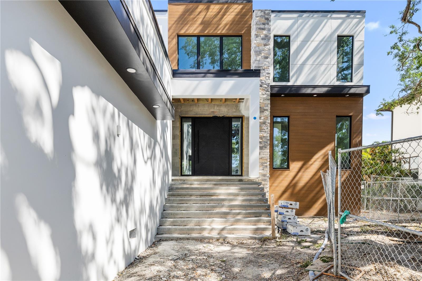 Under Construction. Nearly Complete – Updated Photos Coming - Move-In Ready in Less Than One Week! Modern Luxury with Pool, Spa, Outdoor Kitchen & Designer Finishes.
6 Bedrooms | 5 Bathrooms | 4,891 SF Living | 6,955 SF Total
An exceptional opportunity to own a brand-new luxury residence that is now less than one week from completion. This architecturally striking contemporary home showcases clean lines, 10'8" ceilings throughout the main living areas, expansive walls of glass, and seamless indoor-outdoor living, all thoughtfully designed to deliver a sophisticated Florida lifestyle.
Built with full block-on-block construction and impact-resistant windows, this home offers lasting quality, energy efficiency, and peace of mind. Inside, nearly 4,900 square feet of living space is filled with natural light and enhanced by premium finishes and meticulous craftsmanship throughout.
Designed for both luxury and flexibility, the thoughtfully planned layout includes two primary suites—one on the main level and a second upstairs—making it ideal for multigenerational living, extended guests, or those seeking a private owner's retreat on either floor.
The chef-inspired kitchen features custom cabinetry, quartz countertops, premium appliances, an oversized island, and a designer wet bar, all flowing effortlessly into the expansive great room to create the perfect setting for everyday living and entertaining.
Step outside to your private backyard retreat, complete with a resort-style pool and spa, covered lanai, and a fully equipped outdoor kitchen designed for year-round enjoyment.
Car enthusiasts will appreciate the oversized 3-car garage featuring 18-foot ceilings, offering ample space for oversized vehicles, additional storage, or the future installation of a car lift.
Ideally located near Tampa's premier dining, shopping, entertainment, top-rated schools, and Tampa International Airport, this exceptional residence blends timeless contemporary design with thoughtful functionality and luxury finishes throughout.
With construction entering its final days, now is the perfect time to secure this one-of-a-kind home before it's completed and move-in ready. Schedule your private showing today.