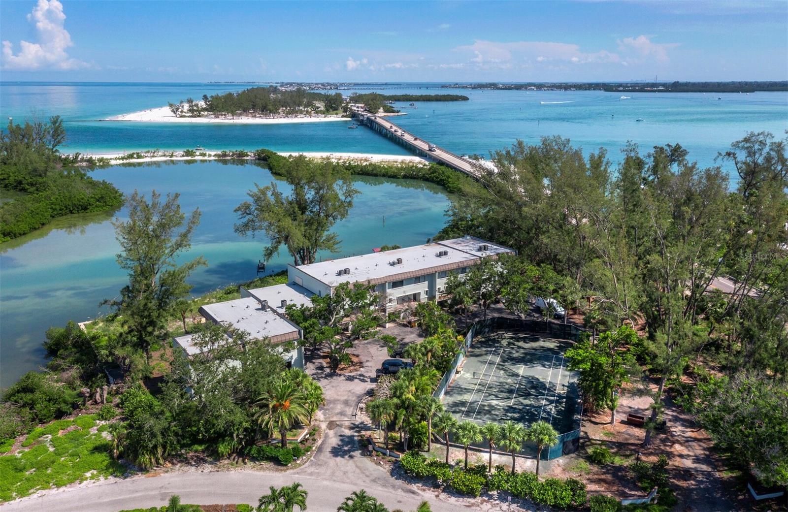 This rare offering is all about the one-of-a-kind BREATHTAKING VIEWS overlooking multiple waterways across Greer island, towards the Intracoastal and out to the gorgeous Gulf of Mexico sunsets! Situated on the quiet north end of Longboat Key in a boutique waterfront, building containing only 9 townhouse style residences: this is island living at its best! It features two bedrooms and 2 and a half baths plus a bonus ground floor air conditioned room and a workshop. Take the steps up to your first living level and enjoy a galley kitchen open to the large great room with sliders to one of 2 outdoor balconies above the ground level, poolside covered porch. On this level is also a half bath. Take the steps up to the second level and the views become even more astounding through the sliders from the Primary ensuite bedroom! Here you will also find the 2nd bedroom and the second bath. Besides the sparkling waterside pool, this small and friendly community has 3 small docks available that allow for easy water access with your kayak, paddleboard or small boat. And don’t forget it has its own clay tennis court as well. One of the nicest and widest beaches on Longboat Key is located just down the street and it wraps all the way around Greer island where you can stand and admire your condo across the waterway from your walk! Multiple restaurants and shopping destinations are within a bike ride or short walk away and the cultural epicenter of downtown Sarasota and Bradenton are just off island when you choose to leave. This may well be the laid-back island life style you are searching for.