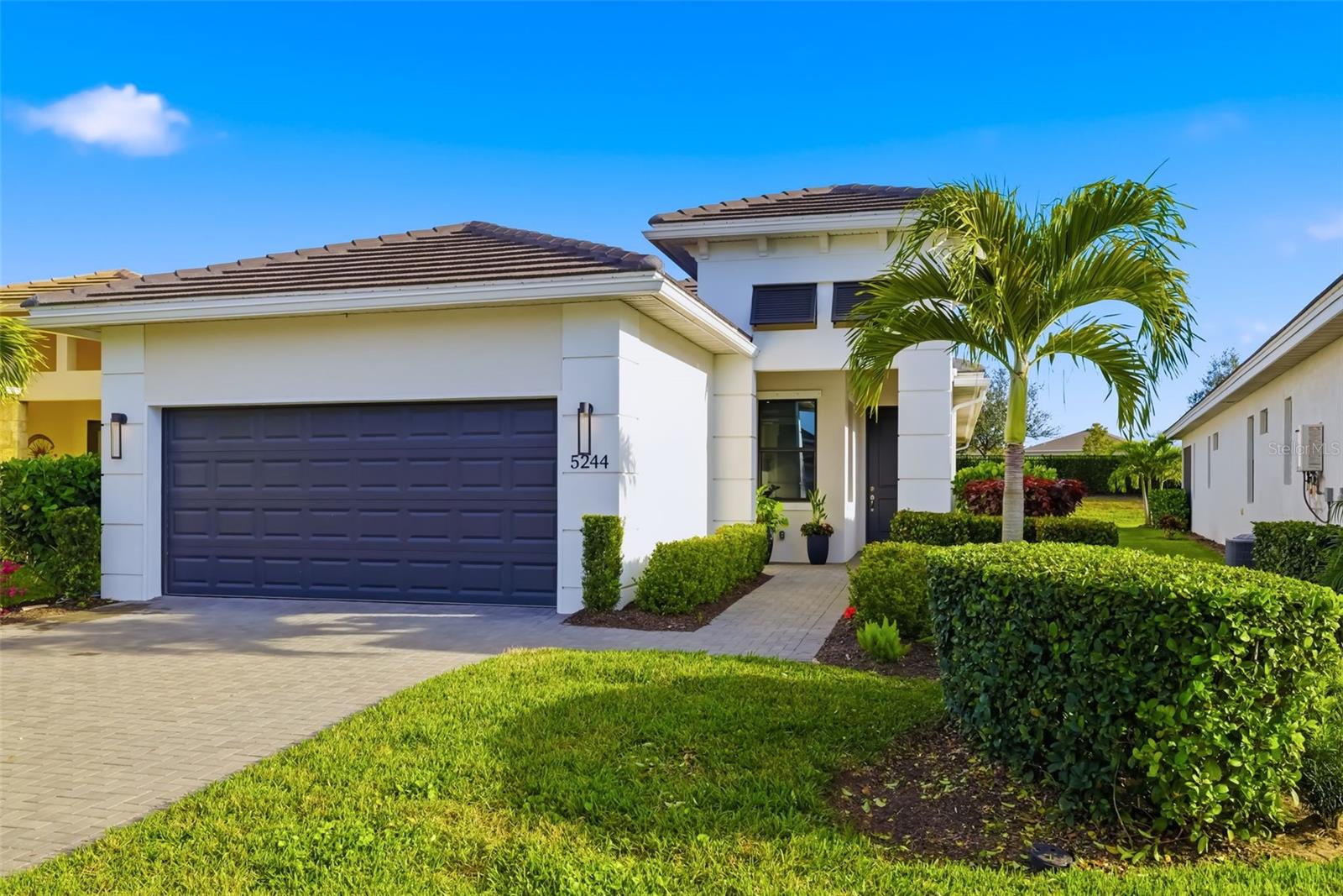 Welcome to a sleek, modern residence in Cresswind at Lakewood Ranch, a premier 55-plus community defined by clean architectural lines and sophisticated design. This 1,852-square-foot home features two bedrooms, two baths, a den, and an open floor plan that enhances functionality and style. The interior showcases a crisp palette of polished white tile and pale walls, with automated window treatments and abundant natural light throughout. The kitchen is designed for seamless integration and visual clarity, offering quartz countertops, high-gloss white cabinetry, an oversized island and a walk-in pantry. The primary suite includes a walk-in closet and a spa-style bath with a walk-in shower accented by a vertical listello. Additional highlights include a den ideal for remote work or media, and a two-car garage with epoxy flooring. Sliding glass doors connect the great room to a spacious screened lanai with stone pavers, ideal for outdoor dining and lounging. Cresswind is a vibrant, amenity-rich community that promotes connection, wellness and leisure through regular resident events, a smart fitness center, resort-style and resistance pools, tennis and pickleball courts, a dog park, and an event plaza hosting food trucks, concerts and social gatherings.