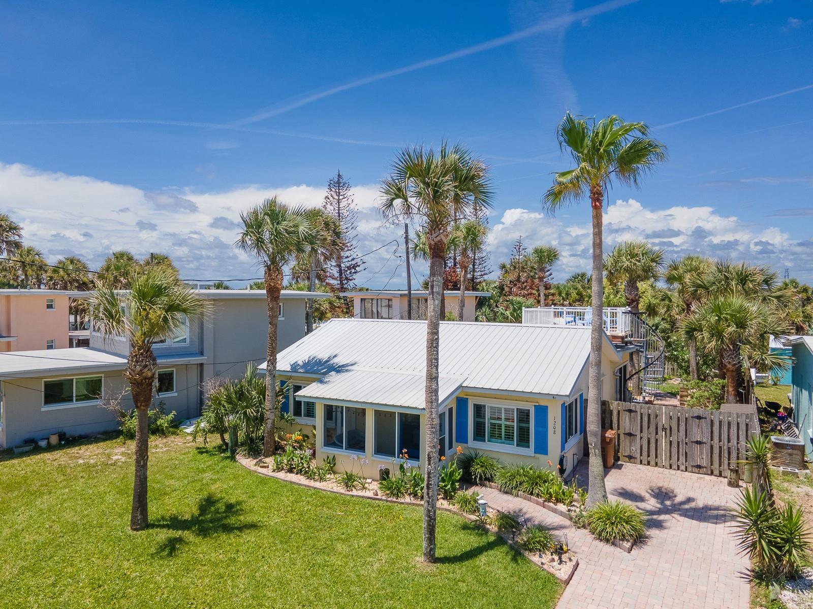 DARLING BEACHSIDE RENTAL JUST STEPS TO THE OCEAN! Enjoy a bird’s eye view from the ROOFTOP DECK! All utilities and services are included in the rent. This home is walkable to all the fun Flagler Beach has to offer yet is also a peaceful retreat with a charming fenced in garden back yard complete with paver paths, a covered porch and a pond! Fully furnished in a casual coastal style, you’ll find everything you need here – just bring your bathing suit and flip flops! Entering from a covered, screened front porch, your living area opens onto a kitchen with a spacious dining island. There’s an abundance of storage in ample wood cabinetry and even a built in desk if you must work. Beyond the kitchen is a generously sized Florida room under air with a dining table and seating. The 2 bedrooms, each with adjoining full bath, offers privacy with one located toward the front of the home and the other off the Florida room. Step outside through sliding glass doors to your private garden sanctuary or take the spiral staircase to the rooftop deck. Flagler Beach still retains that old Florida beach town vibe, and there is endless fun and entertainment from this location an easy walk, bicycle or golf cart ride away. From the beach boardwalk and Pier, dozens of dining establishments from super casual to refined, one-of-a-kind boutiques, regularly scheduled events at Veteran’s Park, in addition to recreational opportunities at parks and the Intracoastal boardwalk, you don’t have to even start your car. Need more excitement? Historic St Augustine is just 30 minutes north, and world-famous Daytona Beach is just 30 minutes south. Whether you just need a recharge or are considering this area for a home, this is the perfect spot to call headquarters for a time.
