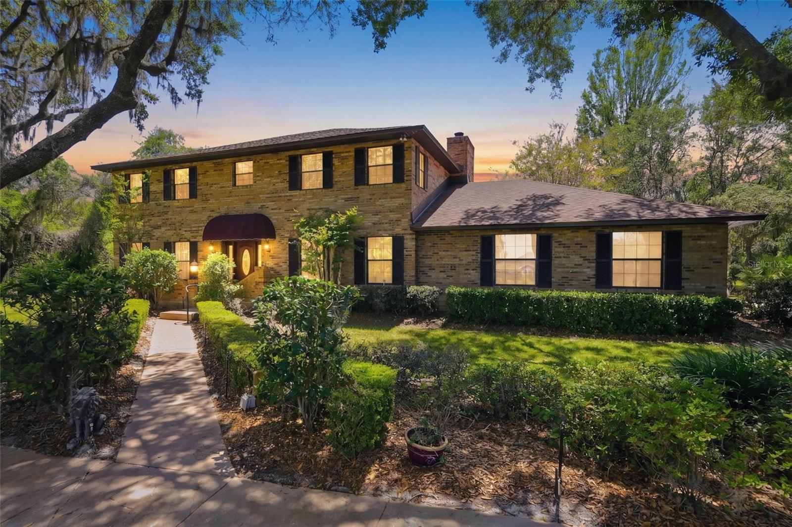 One or more photo(s) has been virtually staged. Welcome to this Beautiful 4 Bedroom 3 Bath custom-built brick estate set on 1.2 acres of lush, mature landscaping. Surrounded by grand oak trees and natural beauty, this exceptional property offers a rare sense of privacy and tranquility while remaining conveniently located close to Mount Dora!  From the moment you arrive, a circular driveway, manicured hedges, and an inviting walkway guide you to a warm and welcoming front entrance, complete with a classic covered portico. The home’s traditional two-story design showcases enduring craftsmanship and timeless curb appeal. Inside, you’ll discover 3,744 square feet of spacious living, ideal for both everyday comfort and entertaining. The family room is a standout feature, offering a dramatic floor-to-ceiling brick fireplace complemented by custom built-ins, creating a warm and inviting gathering space. The expansive main bedroom is a true retreat, stretching the full length of the home and featuring its own wood-burning fireplace with a beautiful marble hearth. The eat-in kitchen overlooks the private backyard, providing a peaceful setting for everyday meals. It is equipped with Corian countertops and stainless steel appliances, blending functionality with style.
Enjoy year-round relaxation in the large screened-in Florida room, recently enhanced with a stunning wood Cedar ceiling that adds warmth and a great place for back yard BBQ's and morning coffee time. Additional features include a spacious laundry room complete with a folding area, as well as a separate office or craft room—perfect for working from home or pursuing hobbies.
Built by its original owner and lovingly maintained, this home includes all original plans and documentation—an incredibly rare and valuable feature for future customization or expansion. New Roof installed in 2024! Water Heater 2025 (upstairs), Exterior Paint 2024, A/C (downstair unit) 2024. Underground dog security fencing installed with two separate zones, Irrigation system, Massey termite bond in place for years. This is more than just a home—it’s a legacy property filled with character, space, and opportunity. Perfect for buyers seeking privacy, quality construction, and a place to create lasting memories.