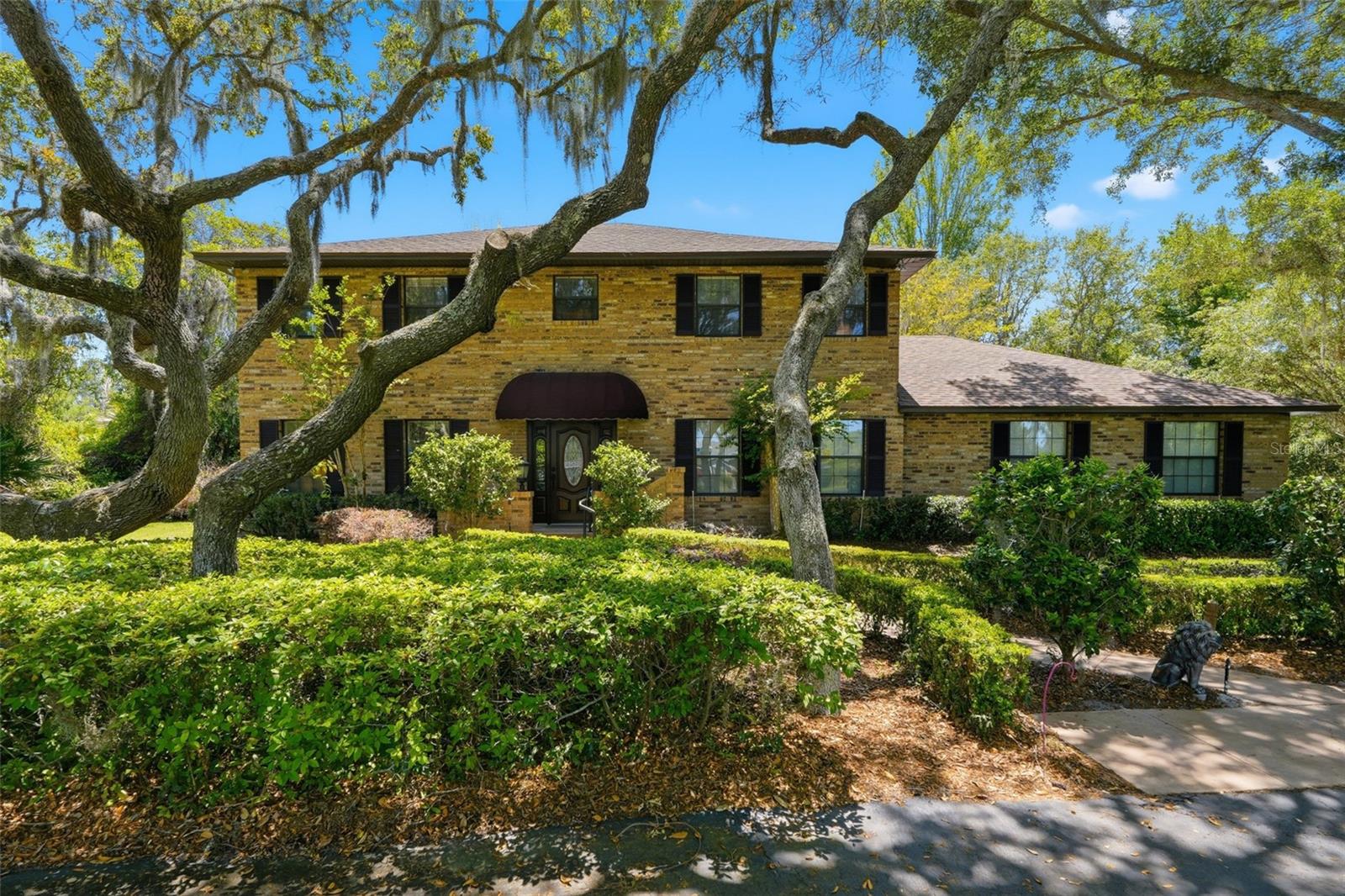 One or more photo(s) has been virtually staged. Welcome to this Beautiful 4 Bedroom 3 Bath custom-built brick estate set on 1.2 acres of lush, mature landscaping. Surrounded by grand oak trees and natural beauty, this exceptional property offers a rare sense of privacy and tranquility while remaining conveniently located close to Mount Dora!  From the moment you arrive, a circular driveway, manicured hedges, and an inviting walkway guide you to a warm and welcoming front entrance, complete with a classic covered portico. The home’s traditional two-story design showcases enduring craftsmanship and timeless curb appeal. Inside, you’ll discover 3,744 square feet of spacious living, ideal for both everyday comfort and entertaining. The family room is a standout feature, offering a dramatic floor-to-ceiling brick fireplace complemented by custom built-ins, creating a warm and inviting gathering space. The expansive main bedroom is a true retreat, stretching the full length of the home and featuring its own wood-burning fireplace with a beautiful marble hearth. The eat-in kitchen overlooks the private backyard, providing a peaceful setting for everyday meals. It is equipped with Corian countertops and stainless steel appliances, blending functionality with style.
Enjoy year-round relaxation in the large screened-in Florida room, recently enhanced with a stunning wood Cedar ceiling that adds warmth and a great place for back yard BBQ's and morning coffee time. Additional features include a spacious laundry room complete with a folding area, as well as a separate office or craft room—perfect for working from home or pursuing hobbies.
Built by its original owner and lovingly maintained, this home includes all original plans and documentation—an incredibly rare and valuable feature for future customization or expansion. New Roof installed in 2024! Water Heater 2025 (upstairs), Exterior Paint 2024, A/C (downstair unit) 2024. Underground dog security fencing installed with two separate zones, Irrigation system, Massey termite bond in place for years. This is more than just a home—it’s a legacy property filled with character, space, and opportunity. Perfect for buyers seeking privacy, quality construction, and a place to create lasting memories.