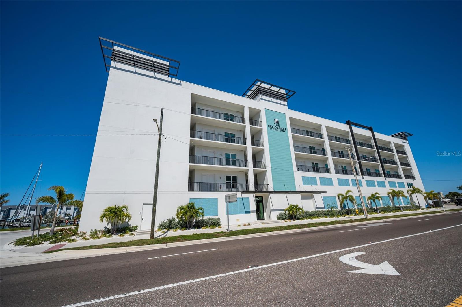 Indulge in Elevated Coastal Luxury in this Like-New, Waterfront End Unit Condo at The Residences at Town Center, an EXCLUSIVE 27-unit waterfront enclave in the HEART of Madeira Beach. Perched on the second-floor corner with expansive Harbor and Intracoastal views, this 3BR, 3BA Coastal contemporary, END UNIT residence offers over 1800 sq ft of refined interior living plus a 28-ft balcony that captures glowing sunsets and gentle waterside breezes.  Also included is a private rooftop cabana (17) with sweeping Bay views, two under-building parking spaces and a dedicated storage room. Inside this LUMINOUS corner residence of distinction, the open-concept design is both elegant and inviting with expanded windows, elevated finishes, and the effortless charm of refined beachside living with soaring 10-ft ceilings all creating a light-filled, sophisticated atmosphere. The designer seaside-luxury Kitchen showcases quartz countertops, solid surface backsplash, solid wood 42-inch custom cabinetry, stainless steel appliances, entertainment sized center island and elegant finishes that amplify everyday living.  Other design-forward interior finishes with refined beachside elegance include porcelain tile plank flooring, impact-rated windows and doors, plantation shutters, electric shades, a large utility room with full sized washer & dryer and a thoughtfully designed split-bedroom layout to include a waterfront Primary Suite with a spa-like bath and walk-in closet that will provide both comfort and privacy along with a sense of quiet exclusivity. This boutique waterfront community built in 2024 offers resort-style amenities including a heated waterfront Inground pool and spa, fitness center, community center / clubhouse with a full kitchen and a spectacular rooftop terrace with 360-degree views stretching from the Gulf beaches to the downtown St. Petersburg skyline. Two assigned, under-building and ample guest parking spaces along with golf cart parking and pet-friendly policies with no size restrictions enhance the effortless lifestyle. Located steps from local dining, boutique shopping, the upcoming Beachmaker Resort by Marriott, and the sugar-soft sands of Madeira Beach, this EXQUISITE residence delivers an unparalleled blend of luxury, convenience, and coastal serenity. With 30-day minimum rentals, it offers exceptional flexibility for full-time living, a seasonal retreat, or investment potential. The Residences at Town Center, where elevated design, tranquil water views, and resort-style amenities come together for an UNMATCHED coastal lifestyle.