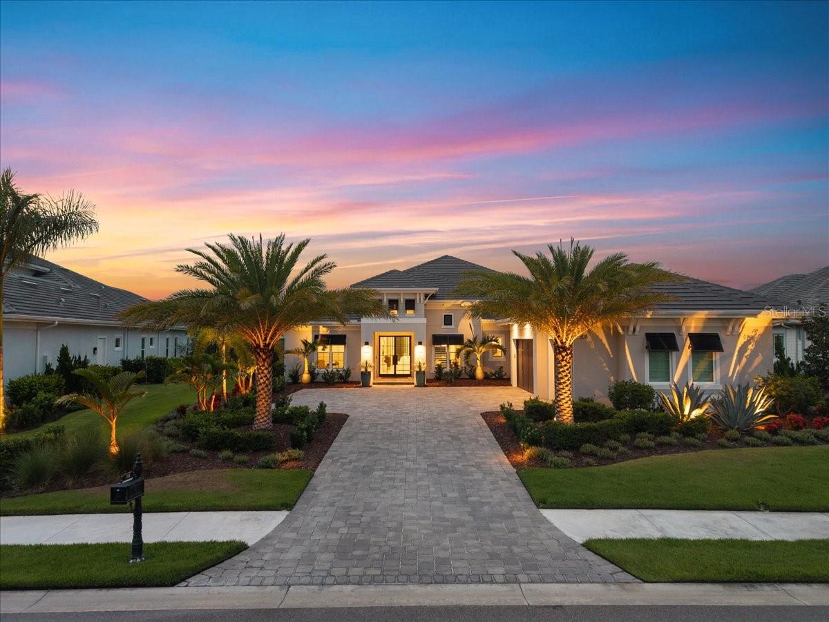 Welcome to your fully upgraded, luxurious residence in The Lake Club!  This opulent home exhibits quality craftsmanship from Stock Luxury Homes across 3,754 SF of functional space including 4 true bedrooms all with walk in closets, 4 bathrooms, great room floor plan, study and bonus room with a closet so has the potential for a 5th bedroom.  Sunset views overlooking the lake in the evenings to the lush surrounding landscaping, this oasis represents the best of complete PRIVACY with the luxury lifestyle in Lakewood Ranch without the wait or hassle of new construction.  Enter through a custom iron door to customized interior finishes throughout with wood look porcelain plank tile, coffered ceiling, designer light fixtures, custom window treatments, custom closets, and Sonos in 7 rooms including the garage. The central great room is the ideal place to gather with a full wall of impact sliding glass doors for seamless indoor and outdoor entertaining. The outdoor oasis has a custom, heated, saltwater pool and spa that takes center stage with two sunshelfs, umbrella holders, and water feature bowls, all framed by panoramic screen enclosures that highlight the views. Also enjoy cozy evenings by the fireplace, and meals alfresco from the outdoor kitchen with Lynx grill and sideburner. Indoors you can dine in the kitchen dinette on weeknights, or in the formal dining room with designer grasscloth wallpaper for elegant occasions. The chef’s kitchen surpasses expectations with a central island, quartz counters, custom cabinetry with extra upper display cabinets, walk-in pantry with cabinetry door, an additional integrated pantry tower with roll-out shelving, reverse osmosis system, and a Jenn-Air stainless steel appliance suite including two dishwashers, gas cooktop, built-in oven and microwave set, and warming drawer.  The butler’s wet bar is great for parties and even includes Jenn-Air ice maker and wine refrigerator. The primary suite with tray ceiling and French doors to the lanai also has dual walk-in closets. The en-suite bathroom is a spa experience with a long vanity of dual sinks, makeup vanity, quartz counters, and walk-in shower with full-height glass enclosure. When you need to work, the private study with double doors and designer grasscloth wallpaper is the perfect location. The expansive rear bonus room offers the ultimate flexibility with a dry bar and beverage refrigerator for entertaining and a built-in closet for storage. Guests will find comfort in three guest suites, two of which have their own private en-suite bathrooms, and the last bathroom has dual function as a pool bath.  Even doing laundry is a joy in this home with two sets of stacking washer and dryer, custom cabinetry, and plenty of counter space.  Don’t forget about the 3-car garage that’s completely insulation so you’ll even stay cool during the summer, EV charger pre-wire and expanded driveway. Peace of mind is secured with impact windows and doors, whole-house Aquasana water filtration and softener systems, smart home pre-wires and solid-core bedroom doors. Conveniently located, you will be mere moments away from the amenities and luxuries of award-winning Lakewood Ranch including shopping, dining, events, farmers markets, parks, and more. The Lake Club is an exclusive premier, gated community with a Grande Clubhouse, restaurant, pool, tennis, pickleball and more. It’s time to stop browsing at homes because this home has it all and is ready for you.
