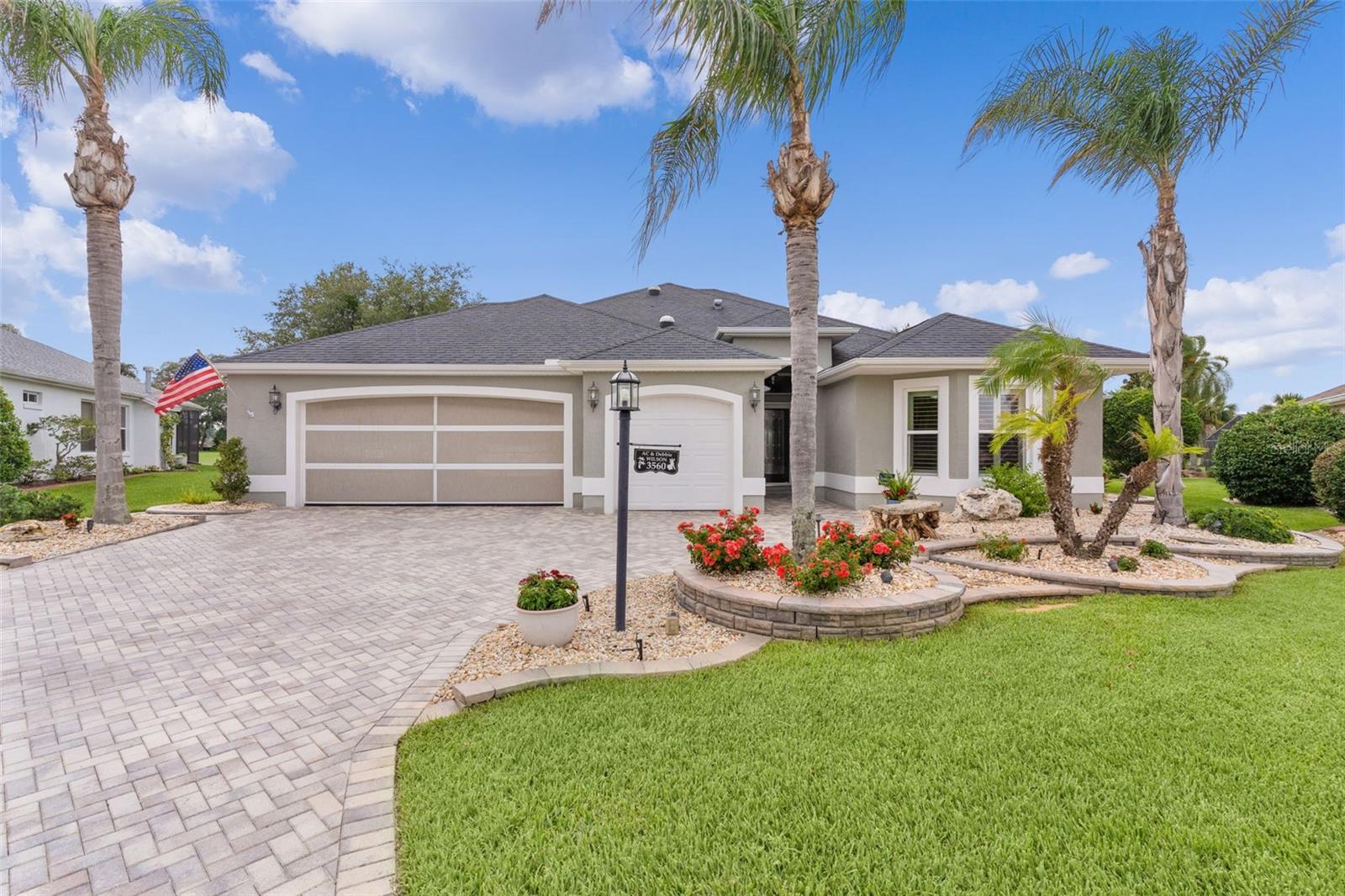~NO BOND~ ~PANORAMIC GOLF COURSE VIEW~ ~SALTWATER POOL~ ~HOT TUB~ ~FURNISHED~ ~VERY PRIVATE~ ~2015 ROOF & HVAC~ ~2018 TANKLESS HOT WATER HEATER~ Experience resort-style living in this beautifully furnished CUSTOM GARDENIA in the sought-after Village of GLENBROOK, perfectly positioned on the GLENVIEW CHAMPIONSHIP GOLF COURSE – Fox Run #3 with breathtaking golf course views! This exceptional POOL AND SPA HOME combines luxury, comfort, and outdoor living in one remarkable package.
Outstanding curb appeal begins with a BRICK PAVER DRIVEWAY leading to a spacious 2-car garage plus GOLF CART GARAGE, complete with EPOXY flooring, built-in cabinets, ELECTRIC SCREEN, and attic stairs for additional storage. Inside, soaring VAULTED ceilings, CROWN molding, PLANTATION SHUTTERS, and CERAMIC tile flooring throughout create an elegant and inviting atmosphere. The spacious living room features UPGRADED lighting, 2 ceiling fans, CUSTOM BUILT-INS, and a stunning FIREPLACE, making it the perfect place to gather and relax. The chef-inspired kitchen offers UPGRADED cabinetry up to the ceiling, GRANITE countertops, STAINLESS STEEL appliances, TILE backsplash, under and over cabinet lighting, ROLL-OUT CABINETS, a closet pantry, and a bright eat-in area. Adjacent to the kitchen, the dining room features VAULTED ceilings, CROWN molding, and a SOLAR TUBE that fills the space with natural light. A convenient BUTLER’S PANTRY adds style and functionality. The luxurious primary suite features private lanai access, PLANTATION SHUTTERS, 2 ceiling fans, VAULTED ceilings, CROWN molding, FIREPLACE, and 2 WALK-IN closets, one of which includes a WASHER, DRYER and PULL-DOWN IRONING BOARD, and a SOLAR TUBE. FRENCH DOORS lead you into the ensuite bath boasting a LARGE WALK-IN shower, OVERSIZED SOAKING TUB, DUAL sinks, linen closet, UPGRADED cabinetry, and GRANITE countertops. The guest wing offers privacy and comfort with 2 spacious bedrooms featuring CROWN molding, PLANTATION SHUTTERS, and built-in closets. The guest bath includes a LARGE WALK-IN SHOWER, UPGRADED cabinetry, GRANITE countertops, and CROWN MOLDING. Step outside to an INCREDIBLE OUTDOOR LIVING SPACE designed to take full advantage of the spectacular golf course setting. The expansive lanai features textured flooring, 2 ceiling fans, an OUTDOOR KITCHEN with stone countertops, PERGOLA brick paver patio, PRIVATE OUTDOOR SHOWER, and a HOT TUB. The SALTWATER POOL overlooks the lush fairways, creating a truly unforgettable backdrop for entertaining or unwinding. The pool is heated with gas and SOLAR HEAT and equipment is 2018. An additional CLIMATE-CONTROLLED STORAGE ROOM provides valuable extra space. With upgrades like a PEGASUS WATER SOFTENER and WATER PURIFICATION SYSTEM, Pella hurricane strength sliding doors, stunning views, and exceptional indoor-outdoor living, this Glenbrook Gardenia is a rare opportunity to own a golf-front paradise in The Villages. It comes fully FURNISHED with décor that was built specifically for this expanded home. There are 7 TVs, all curtains were personalized to the windows, and the furniture, inside and outside, are all from high end manufacturers. Location, location, location for this incredible property. Minutes from CR466 with shopping, dining and medical and a short golf cart ride to Spanish Springs Town Square and Lake Sumter Landing. Very close to Glenview Country Club as well as the Savannah Center. Multiple executive golf courses are also close by. A MUST SEE!