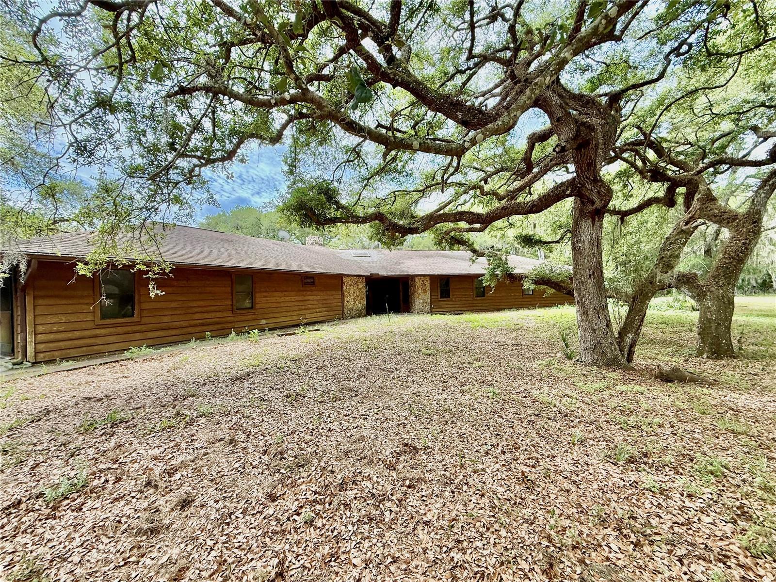 Welcome to your own private slice of country living with almost 5 acres of peaceful, open land where country living meets everyday comfort. This property provides a serene retreat while remaining just minutes from New Smyrna Beach, Edgewater, local parks, river, boat ramps and popular biking/walking trails. Enjoy the quiet life in this 3 BD 2.5 BA custom built unique home with large rooms, it is a must see! A renovated kitchen showcases modern updates and flows effortlessly into the dining area, creating a great space for everyday living or entertaining. Huge stone fireplace can warm the entire living area in the winter. House has generator & water softener. Back of the house has a neat wrap around screened porch overlooking mature trees, open green space and quiet rural scenery. This home is just waiting for its new owners to bring it back to life. Property is fenced with a gate at the drive ready for you to bring your live stock and plant your gardens. Offers the freedom of no HOA and captures the true essence of rural Florida living. The perfect location (No HOA) for anyone who owns needs to park equipment, trucks, an RV or any other type of vehicle on the property. New roof installed 6/2026. Please note that all measurements and information are deemed accurate but should be verified by the buyer.