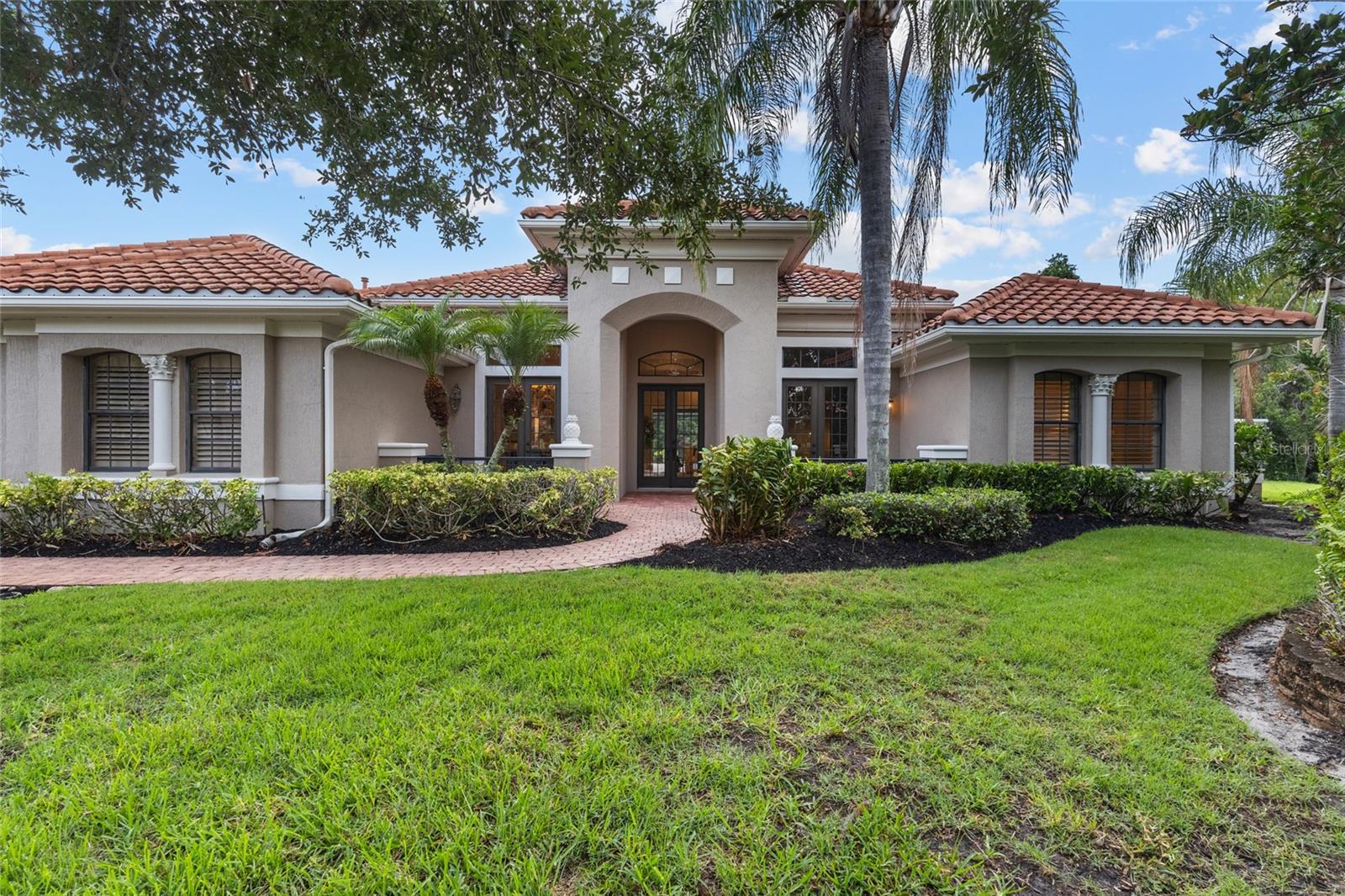 Perfectly positioned on a quiet cul-de-sac overlooking a tranquil pond, this exceptional custom residence offers refined Florida living on an expansive homesite of more than half an acre within the prestigious Lakewood Ranch Country Club. Offering 3 bedrooms, 3 bathrooms, a private executive office, and a versatile bonus room with its own private bath, this beautifully maintained home blends timeless Mediterranean architecture with an open-concept design, a desirable split floor plan, and effortless indoor-outdoor living. From the moment you step through the grand double-door entry, soaring ceilings, elegant columns, abundant natural light, and architectural details create an unforgettable first impression. Designed for entertaining, the formal dining room features a custom built-in buffet with granite countertops, abundant cabinetry, and an oversized mirrored accent wall, while the formal living room is anchored by a natural gas fireplace and expansive sliding glass doors framing peaceful pond views and opening to the resort-style lanai. Just off the foyer, a private executive office with custom built-ins creates an ideal work-from-home space. The beautiful kitchen serves as the heart of the home, featuring refinished cabinetry (2026), granite countertops, a center island, abundant storage, a breakfast nook overlooking the pool, and an elegant butler's serving station with glass-front display cabinetry connecting the kitchen and formal dining room. Beyond the kitchen, the spacious family room offers seamless access to the lanai, creating effortless everyday living and entertaining. Plantation shutters, crown molding, and quality craftsmanship enhance the home's sophisticated design. Privately positioned, the owner's retreat offers lanai access, a secluded courtyard with an outdoor shower, a custom walk-in closet, and a spa-inspired bath with dual sinks, a soaking tub, and an oversized walk-in shower. Designed with a desirable split floor plan, the guest accommodations include a spacious bonus room with tranquil pond views, lanai access, and its own private full bath—ideal as a guest retreat, 4th bedroom, media room, fitness studio, or lounge. Two additional guest bedrooms and a full bath complete the private guest area. Designed for Florida living, the expansive lanai features two covered entertaining areas, a sparkling pool with waterfall, above-ground spa, a built-in natural gas grill, and serene pond views. Recent improvements include a tile roof (2018), refinished kitchen and bathroom cabinetry (2026), fresh interior and exterior paint (2026), a new pool pump (2024), and pool heater (2025). Additional highlights include natural gas service to the fireplace, water heater, dryer, and outdoor grill, a gas connection for the kitchen range, a whole-home stereo system, an oversized laundry room with cabinetry and utility sink, and a three-car garage. Optional membership levels are available through the Lakewood Ranch Golf & Country Club, offering championship golf, tennis, pickleball, fitness, dining, and an exceptional club lifestyle. Beautifully refreshed and meticulously maintained, this remarkable residence offers timeless elegance, exceptional privacy, and one of Lakewood Ranch's premier luxury lifestyles.