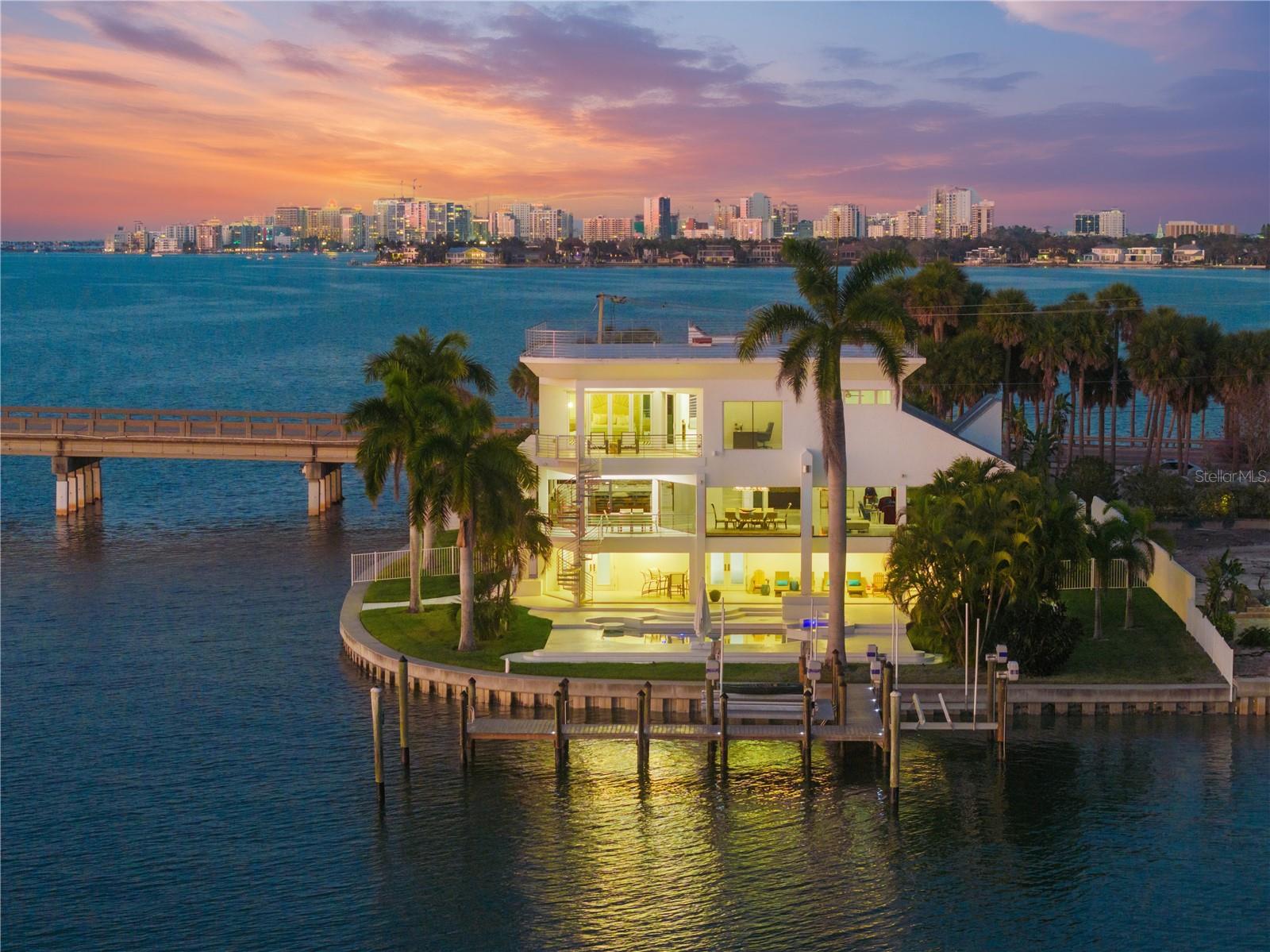 Welcome to 1400 Siesta Drive, where refined waterfront living becomes your everyday reality. This home is quietly tucked away behind a  gated entrance, with an additional secondary gate providing exclusive access to the residence. Thoughtfully designed to embrace breathtaking, unobstructed views of Sarasota Bay, this modern residence is a showcase of light, space, and coastal elegance. Expansive floor-to-ceiling windows frame the ever-changing scenery, offering front-row views of passing boats and unforgettable sunsets from nearly every room. The primary suite is a private sanctuary, featuring a generous walk-in closet, a spa-inspired ensuite bath, and a dedicated office—each enhanced by stunning bay views. Outdoors, your personal oasis awaits with a heated pool, abundant sun-drenched lounging space, and a newly constructed dock ready for effortless boating and waterfront adventures. Ideally located near Sarasota’s world-class dining, shopping, and cultural attractions, this exceptional bayfront retreat offers the perfect balance of privacy and convenience. Offered turn-key furnished, this is a rare opportunity to step seamlessly into an elevated waterfront lifestyle.
