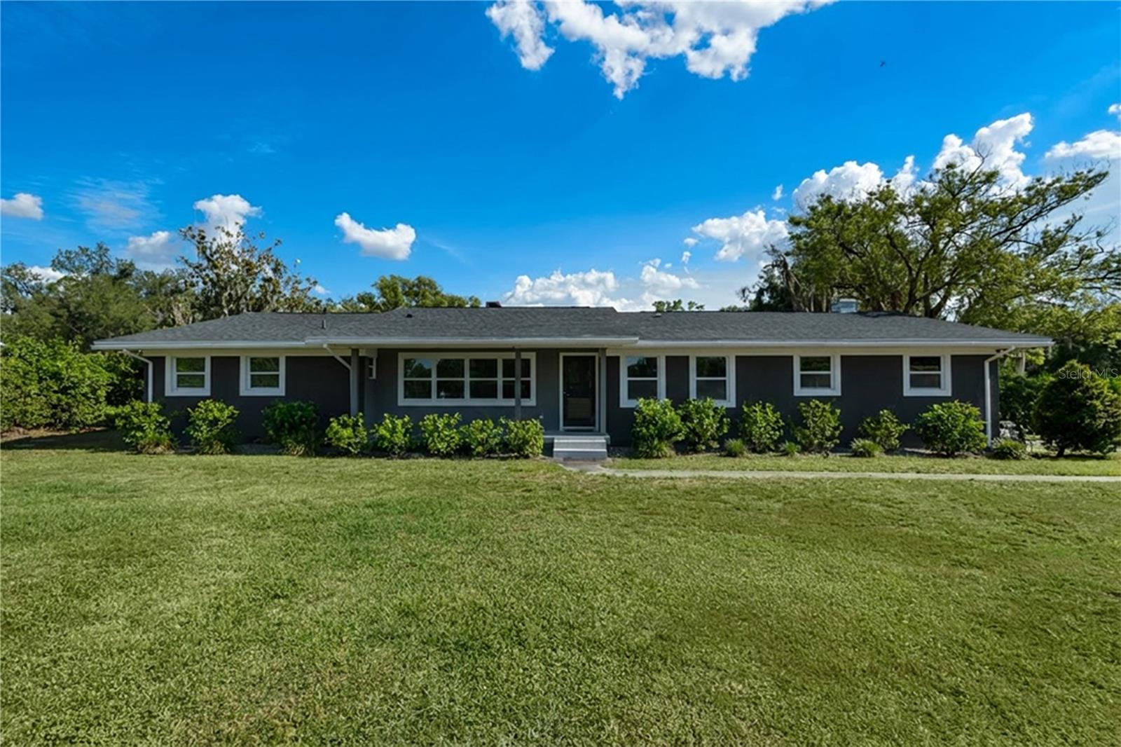 Welcome to this fully renovated modern property situated on 4.48 acres with peaceful water views. This stunning 4-bedroom, 2.5-bath home has been completely transformed from top to bottom with sleek finishes, and thoughtful upgrades designed for both everyday living and entertaining. 

The heart of the home is a custom-designed chef’s kitchen featuring waterfall quartz countertops, high-end stainless-steel appliances, and a large island overlooking the family room and secondary dining space. The wall of sliding glass doors floods the living spaces with natural light while creating a seamless indoor-outdoor connection to the peaceful backyard and pond views. Just off the kitchen and dining area, is an expansive walk-in pantry providing additional prep space, storage, and organization.

Designed with functionality and entertaining in mind, the home offers multiple spacious gathering areas, including a second living room and additional dining space. Whether hosting holidays, dinner parties, game nights, or simply enjoying everyday life, the layout offers the perfect combination of openness and flexibility.

The spacious primary suite is a true owners retreat with a sliding glass door, providing access to the backyard and an oversized room-style walk-in closet. The luxurious spa like primary bathroom features floor-to-ceiling custom tilework, a spacious glass-enclosed walk-in shower with dual shower heads, floating vanity with dual sinks, built-in custom shelving, and sleek modern finishes throughout. 

Two additional spacious bedrooms and a renovated bathroom complete the main bedroom wing, while an additional front room offers flexibility for a fourth bedroom, private office, or guest space.

Updates include new exterior stucco and paint, all-new plumbing, new duct-work, AC, main electrical panel, water filtration system, light fixtures, flooring, windows, doors, tankless water heater, and a 2020 roof—providing long-term efficiency and peace of mind for years to come. 

The laundry area is located in the 2-car garage, also including a dedicated utility/storage room housing the water filtration system and tankless water heater. Outside, the expansive 4.48-acre property offers endless possibilities with room for animals, recreational vehicles, gardens, or creating your own private outdoor oasis. With NO HOA and a large flat usable lot, this property offers flexibility rarely found this close to daily conveniences. At the back of the property is a picturesque pond, shared by only four properties. 

Located in top-rated school districts and within walking distance to Lakeland Highlands Middle School. Across the street from the property is rear road access leading directly to Publix, shopping, restaurants, and everyday conveniences. Additionally, only seconds away from S Florida Ave providing even more shopping and restaurant options. 

262 feet of road frontage, Residential Low -2 (2 homes per acre, minimum 15,000 square foot lots) Conversations have already been started with the county regarding rezoning or subdividing. This property offers not only modern living and privacy, but also future development potential. This is a rare opportunity to own a fully renovated estate combining acreage, convenience, and long-term flexibility.