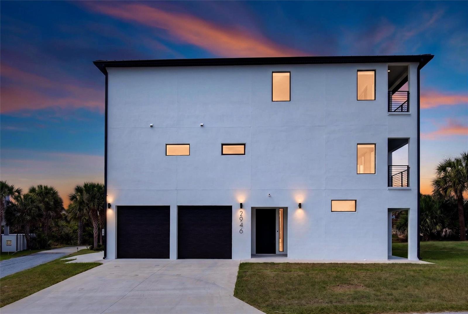 This newly constructed three-story coastal residence is a rare opportunity to own a home that not only captures ocean views, but is built with a level of engineering, durability, and intentional craftsmanship that is seldom found in today's coastal construction. Located just steps from deeded beach access, the home blends elevated living with long term performance and flexibility. Modern, aesthetically on point, and remarkable on every level, both in design and construction. Constructed entirely of block with poured concrete reinforcement approximately every 14 inches across all levels, this home was designed from the ground up for strength and longevity. The exterior is further enhanced by a specialty aluminum standing seam roof by Sunnyland, a premium upgrade well beyond standard materials, along with impact and wind rated hurricane windows designed for enhanced coastal protection. Smart Guard custom shutters protect all first-floor openings and additional upper-level sliders, with full hurricane shutter coverage providing added security and peace of mind during extended absences. Full spray foam insulation throughout all walls, ceilings, floors, and even floor joists create a tightly sealed, energy efficient environment while also contributing to interior comfort and sound control. Inside, the home offers a seamless balance of functionality and refined finishes. A private elevator services all three levels, complementing a wide custom oak staircase and making the home fully accessible. Each of the three bedrooms is designed as a private en suite, featuring wheelchair accessible wet room bathrooms with walk in rain showers, custom Italian finishes, and thoughtful design throughout. The primary suite is further elevated by a freestanding soaking tub and upgraded features including Bluetooth enabled exhaust fan lighting and audio. The main living areas are designed to maximize light, openness, and connection to the coastal surroundings. Expansive slider windows invite natural light while framing the views. Sweeping ocean views extend from the main living areas and primary suite, complemented by expansive balconies that span the full ocean-facing façade, including a full-width private balcony off the primary suite. Multiple Trex balconies with custom railings offer elevated outdoor living and ocean view vantage points across the second and third levels. The kitchen reflects both form and function, with custom cabinetry including pull out interior drawers, quartz countertops, Bosch appliances, an induction cooktop, built in organizational systems, and dedicated hidden appliance storage for a clean, intentional look. Italian tile on the first floor is installed over a Schluter Systems uncoupling and waterproofing system, an advanced installation method designed to help reduce the risk of cracking and promote long term durability. Additional systems and features continue the theme of quality construction and livability, including three independent HVAC systems with dehumidifier settings, a 300-amp dual panel electrical service, whole house water filtration, integrated security cameras, and a fully finished oversized garage with dual impact doors, Wi-Fi openers, and secondary access. Motorized garage door openers include extended interior lighting, providing added visibility and functionality within the garage space. The garage and exterior surfaces are finished with a durable polyaspartic coating, and additional utility features