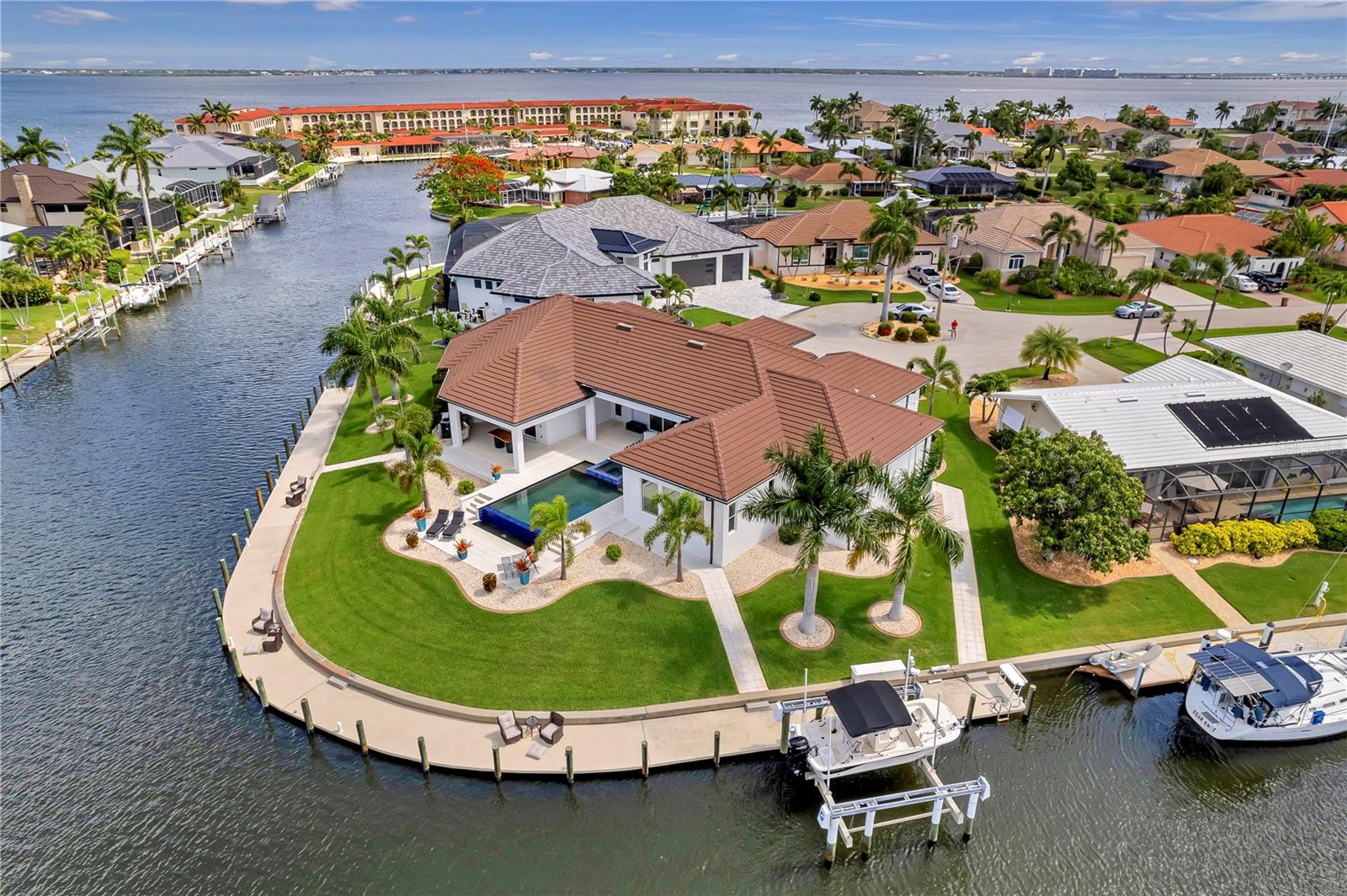 Under contract-accepting backup offers. Positioned on a premier 255-foot waterfront key lot in the heart of Punta Gorda Isles, 2795 Bay Court is a rare expression of modern coastal luxury where architectural sophistication, yachting lifestyle, and intelligent design converge. Custom built by renowned builder PGI Homes, this exceptional residence was crafted for the buyer who values both striking design and uncompromising engineering.
From the moment you arrive, the home commands attention with coquina-wrapped columns, a dramatic illuminated fountain, and custom 10-foot iron entry doors that open into soaring interiors framed by expansive water views. Inside, every detail has been elevated: rich hardwood flooring, illuminated tray ceilings, floating cabinetry, marble feature walls, designer lighting and water views from every room.
The main living space was designed for effortless entertaining and everyday indulgence alike. A stunning chef’s kitchen anchors the home with Cambria quartz waterfall counters, premium appliances, custom cabinetry, oversized island seating, gold glass accents, and an adjoining catering kitchen for seamless hosting. The great room centers around a sculptural marble fireplace wall while opening completely to the resort-style lanai beyond.
Outside, the experience becomes unforgettable.
The infinity-edge saltwater pool and spa spill elegantly toward the water, surrounded by shell stone decking, expansive covered lounging areas, tongue-and-groove wood ceilings, oversized architectural fans, and a fully equipped outdoor kitchen featuring a Lynx rotisserie grill, burner, granite counters, and stainless ventilation hood. Every sunset here feels cinematic.

Designed with boaters in mind, the property offers 255 feet of substantial concrete dockage with integrated utilities, commercial-grade shore power, illuminated bollard lighting, fish cleaning station, and a 30,000-pound lift with quad motors and reinforced pilings, all positioned just moments from open water access to Charlotte Harbor.

The primary suite is a private waterfront retreat complete with custom boutique-style closets, chandelier accents, spa-inspired bath finishes, integrated audio, and panoramic water views. A separate VIP guest suite offers its own entrance, HVAC system, wet bar, wine fridge, icemaker, and blackout shades, creating a true private luxury experience for guests or extended stays.
Beyond its beauty, this home was engineered to perform at an elite level. Features include CAT-5 rated impact glass throughout, a 24KW whole-house Generac generator, three separate Carrier systems, buried propane tank, structured smart-home automation, enterprise-grade WiFi, integrated AI security systems, distributed Sonos and Klipsch audio, dedicated AV infrastructure, Starlink capability, and whole-property app-controlled functionality. 
2795 Bay Court is not simply another luxury waterfront home. It is a meticulously executed private coastal estate built for those who expect exceptional craftsmanship, seamless technology, and next level waterfront lifestyle.