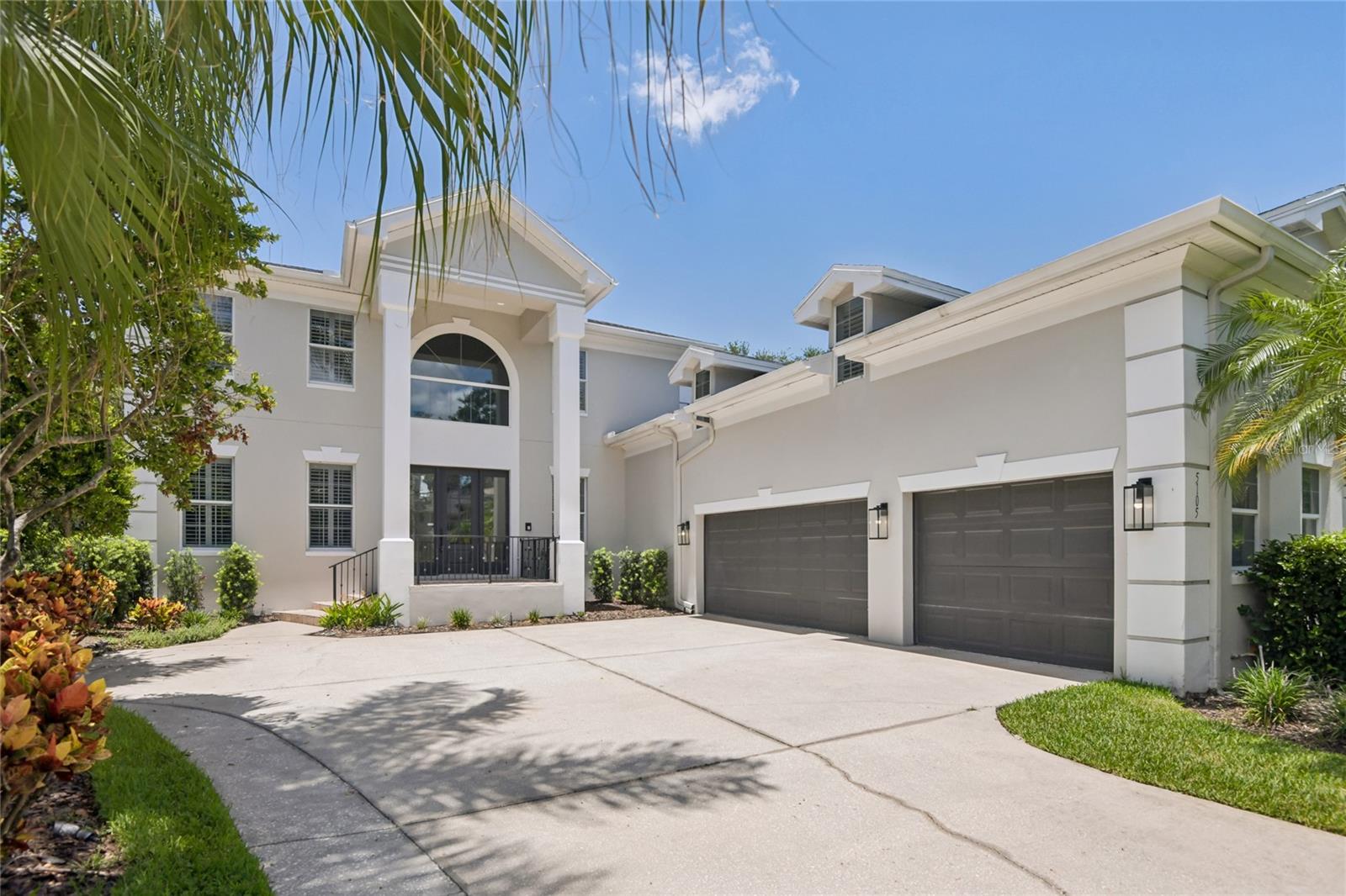 Virtually Staged. A commanding presence in the heart of South Tampa — this stunning two-story estate announces itself with a dramatic columned entry, soaring arched window, tropical landscaping, and a three-car garage that signals the scale and quality waiting inside. The fully reimagined kitchen is the crown jewel of the home. Dual islands — one white quartz, one accented in a bold slate blue — anchor a space defined by white shaker cabinetry with glass uppers, professional-grade stainless appliances, a custom range hood, subway tile backsplash, and glass pendant lighting. Dark hardwood floors run throughout and flow seamlessly into the family room, where custom teal built-ins flank a fireplace — a design moment that is equal parts functional and unforgettable. The primary bath offers a true spa experience: vessel sink double vanity, a deep soaking tub with tile surround, a glass walk-in shower, and a mosaic tile inlay floor detail that adds just the right touch of artistry. Upstairs, a dramatic vaulted bonus room with track lighting, dormer windows, dark hardwood floors, and built-in cabinetry offers endless flexibility — home studio, media room, playroom, or private office. Step outside to a screened lanai with brick pavers, a fully equipped outdoor kitchen with built-in grill and designer hood, and a gorgeous screened pool and spa with a stacked stone water feature wall — the complete Florida outdoor living package. Located in one of Tampa's most coveted zip codes, minutes from Beach Park, Hyde Park Village, and the best dining and shopping South Tampa has to offer.. Included 100-Day Home Warranty with buyer activation