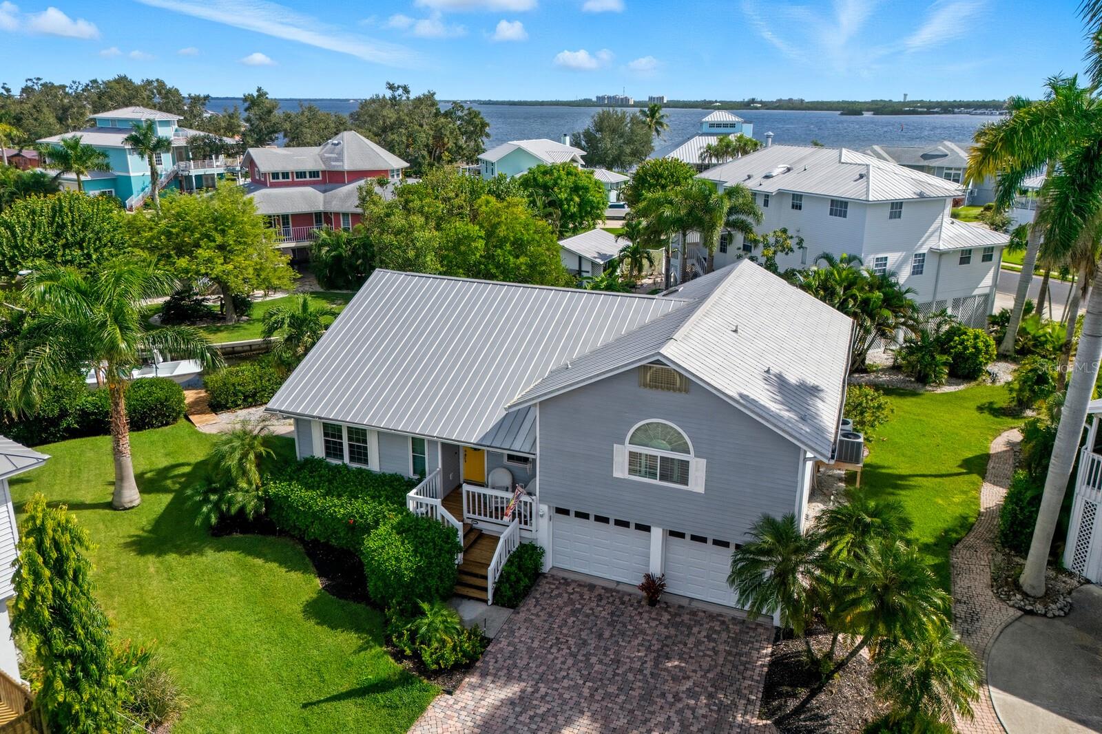 ABSOLUTELY THE BEST WATERFRONT VALUE ON SNEAD ISLAND! WHY BUY A GROUND LEVEL HOME THAT HAS ALREADY FLOODED- THIS ELEVATED HOUSE OFFERS PEACE OF MIND ON THE WATER!!! This custom built, one owner ELEVATED Key West style residence offers the perfect combination of boating access, quality construction, hurricane protection, and coastal lifestyle at a price that is becoming increasingly difficult to find on Florida’s Gulf Coast. Situated on a quiet cul de sac in the desirable Heritage Bay community, this meticulously maintained waterfront home enjoys direct access to Terra Ceia Bay, Tampa Bay, and the Gulf of Mexico with no bridges and is located just a few homes from open water. From the moment you arrive, the curb appeal is undeniable with a metal roof, paver driveway, mature tropical landscaping, covered front porch, irrigation system, and extensive landscape lighting. The owners have taken exceptional care of the property since it was built and have upgraded all windows and exterior doors to HURRICANE IMPACE RATED construction, providing both peace of mind and long term value. Inside, the open floor plan is filled with natural light thanks to soaring vaulted ceilings, expansive windows, and multiple glass doors overlooking the water. The spacious great room serves as the centerpiece of the home and flows seamlessly into the kitchen and dining areas, creating an ideal layout for both everyday living and entertaining. The kitchen features shaker style cabinetry, abundant counter space, stainless steel appliances, and a breakfast bar overlooking the main living area. Adjacent to the kitchen, the dining room offers beautiful water views and includes a dry bar, making it the perfect setting for hosting family and friends. The primary suite is generously sized and features wood flooring, two closets including a large walk in closet, and an ensuite bath with a spacious vanity and walk in shower. Both guest bedrooms are also generously sized and offer their own private ensuite bathrooms, creating a comfortable layout for family and overnight guests. A convenient powder bath and dedicated laundry room with utility sink and additional storage add to the home’s functionality. Outdoor living is where this property truly shines. The covered screened lanai overlooks the canal and features a wet bar along with a pass through window to the kitchen, making outdoor entertaining effortless. Beyond the lanai, a massive wraparound Trex deck provides an incredible space for relaxing, dining, and gathering with guests while enjoying the waterfront setting. A paver walkway leads to the private dock equipped with water, electricity, and a 12,000 pound boat lift. With open water only moments away, you’ll enjoy quick and easy boating access to Terra Ceia Bay, Tampa Bay, the Gulf, waterfront restaurants, fishing destinations, and nearby islands. The oversized three car garage offers tremendous storage capacity and includes a dedicated workshop area that can easily serve as a tackle room, hobby space, or workshop. A rear garage access door provides added convenience for boating and outdoor equipment. Residents of Heritage Bay enjoy access to a community pool and tennis court. Located just minutes from Emerson Point Preserve, the local yacht club, marinas, kayaking trails, bicycle paths, and only about 15 miles from the beaches of Anna Maria Island, this property offers an exceptional waterfront lifestyle. DO NOT WAIT ON THIS ONE!!!
