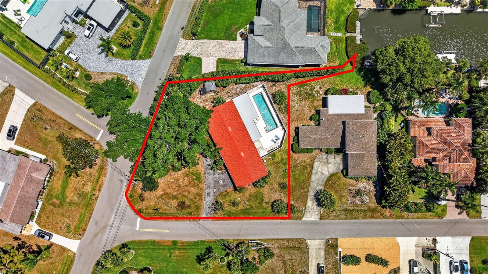 Located in the highly desirable Aqualane Estates, just about a mile from the world-famous Siesta Key Beach and Crescent Beach, and close to local favorite Captain Curt’s Crab & Oyster Bar, this unique property offers an incredible opportunity to own in one of Sarasota’s most sought-after waterfront neighborhoods. Surrounded by million-dollar homes and picturesque canal-lined streets, the setting alone makes this home truly special. Set on an expansive 0.40-acre lot, the property is anchored by a stunning, majestic banyan tree that creates unmatched curb appeal and Old Florida charm. While the home does not offer full canal access, it does feature a small sliver of water frontage, adding to its character. With no HOA, you’ll enjoy added flexibility and freedom rarely found in such a prime location. Additionally, the home is in Flood Zone X and X500 and has never flooded. This oversized lot also presents exceptional potential for redevelopment, with ample space to build a new custom home in line with the luxury properties throughout the neighborhood—making it ideal for investors, builders, or buyers looking to create their dream home. Built in 1956, this classic Florida-style home offers 3 bedrooms, 2 bathrooms, and 2,325 square feet of living space. Inside, you’ll find timeless character throughout, including beautiful terracotta tile flooring accented with unique hand-painted tiles, along with artistic touches carried into the primary bedroom and shower. The outdoor space is designed for enjoying the Florida lifestyle, featuring a large, private pool ideal for laps, all enclosed within a fenced backyard and patio area for added privacy. A two-car garage with an attached workshop provides plenty of room for storage, hobbies, or projects. Recent updates include a 2025 shingle roof and an upgraded lift station for the septic system, offering peace of mind for the next owner. Whether you’re looking to enjoy it as-is, renovate, or build new, this property offers a rare combination of location, lot size, flexibility, and future potential just minutes from the beach, dining, and everything Sarasota has to offer.