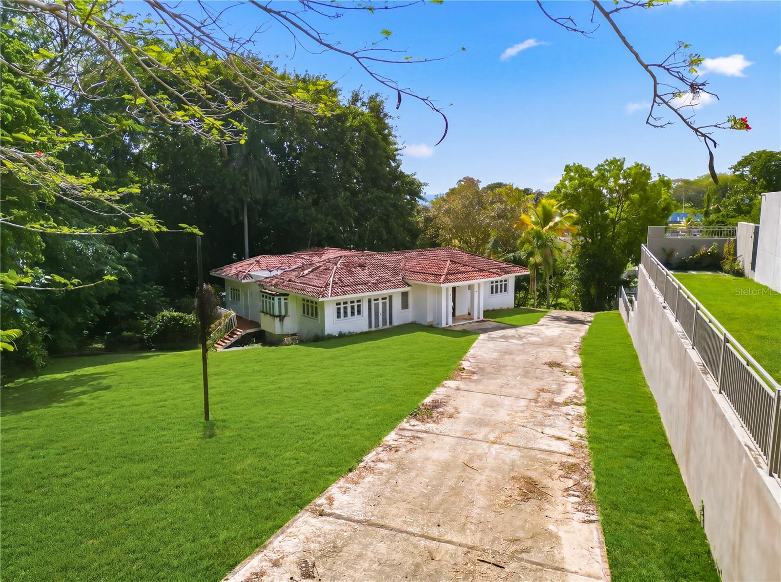 Located in one of Guaynabo’s most exclusive and private communities, this property at Calle Vanda#7 offers a rare balance of tranquility, space, and accessibility. Surrounded by nature and set on a large piece of land, the home feels like a peaceful retreat—quiet, green, and removed—yet still conveniently close to the city and major expressways.

The residence features 6 bedrooms, 5 bathrooms, and approximately 5,830 square feet of living space. It’s an ideal opportunity for a buyer with vision, ready to remodel and shape the home into something truly their own. Balconies and terraces wrap around the property, creating inviting spaces to relax, gather, and enjoy the natural surroundings.

Within a gated community with 24/7 security, this home also benefits from a prime location near some of Puerto Rico’s most prestigious schools, making it a strong choice for families. It’s a place where you can enjoy the feeling of living in the countryside, with the convenience of being right in the heart of Guaynabo.