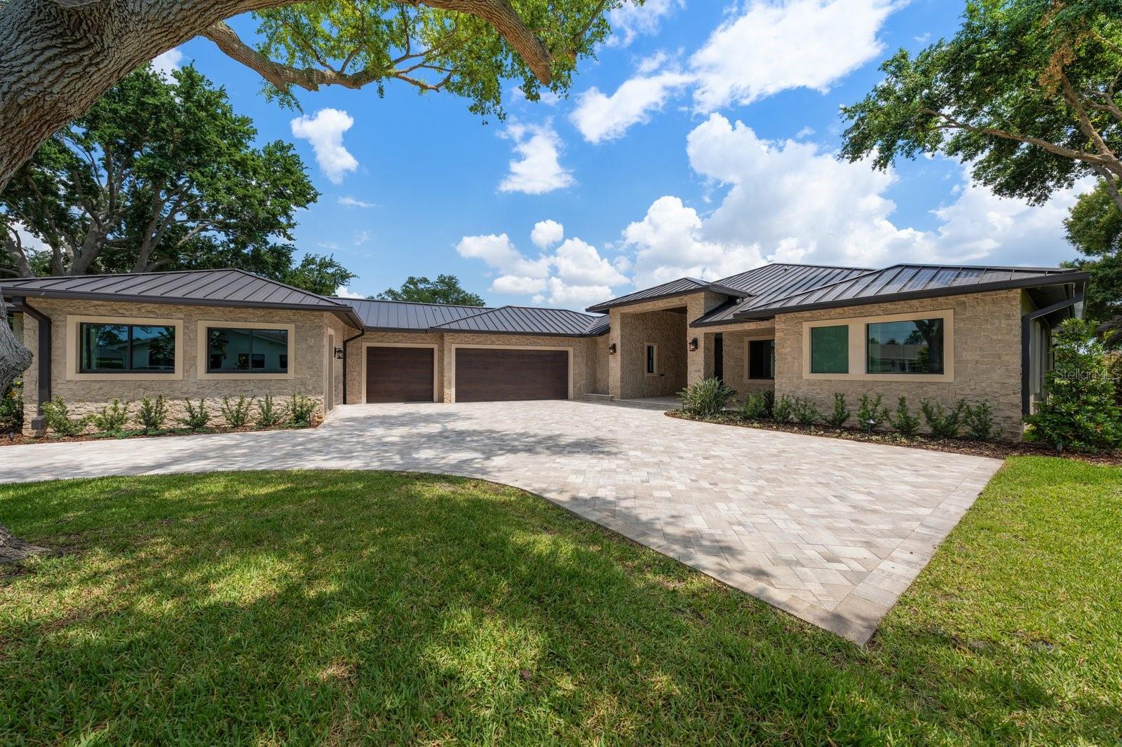 One or more photo(s) has been virtually staged. ONE-OF-A-KIND WATERFRONT ESTATE ON PELICAN GOLF COURSE. Set on a unique, private half-acre cul-de-sac lot overlooking the water and the fairways of the Pelican, this 4 to 5 bedroom, 4 bath residence with a private in-law suite has been completely reimagined into a bold, design-forward showpiece. No detail has been overlooked in this luxury, custom home. The commanding hand-laid stone exterior opens to interiors featuring 10 to 13 foot ceilings with crown molding, luxury hardwood flooring, dramatic designer lighting, and a custom wine bar. New impact windows and sliders flood the home with natural light while capturing spectacular water and golf course views. The stunning chef’s kitchen is a true centerpiece, showcasing illuminated Cristallo quartzite countertops, custom cabinetry, and premium Thermador appliances—perfectly suited for both everyday living and elevated entertaining. The primary suite is a warm and inviting retreat with picturesque course views and a custom gas fireplace. The spa-inspired bath features dual vanities with lighted mirrors, a makeup area, and expansive his-and-hers walk-in closets. The main home offers three additional spacious bedrooms and two beautifully designed baths with luxury finishes. A thoughtfully designed casita features a private entrance, a full custom kitchen, and a beautifully appointed bath with a whirlpool tub and separate shower—ideal for multigenerational living, a guest suite, an office, or whatever you can imagine for this incredible flex space. 
Step outside to resort-style living with a custom heated saltwater pool and spa, set against tranquil water and golf course vistas. Marble pavers span the entire pool deck and covered lanai, creating a seamless space for relaxation and entertaining. Other new features include a standing seam metal roof, dual Trane HVAC systems with all new ductwork, Icynene insulation, dual natural gas tankless water heaters, and a whole-house water treatment system. Nearly 1,100 sq. ft. air-conditioned, finished garage with high ceilings provides year-round comfortable parking and storage. Ample outdoor parking, mature landscaping with custom lighting, a deep well, and a whole house generator complete this one-of-a-kind home. Located just minutes from Clearwater Beach, fine dining, boutique shopping, and premier clubs, including Pelican Golf Club and Belleair Country Club, this exceptional, redesigned residence offers a rare opportunity to enjoy luxury living in one of Florida’s most sought-after coastal golf communities. One or more of these photos are virtually stage.