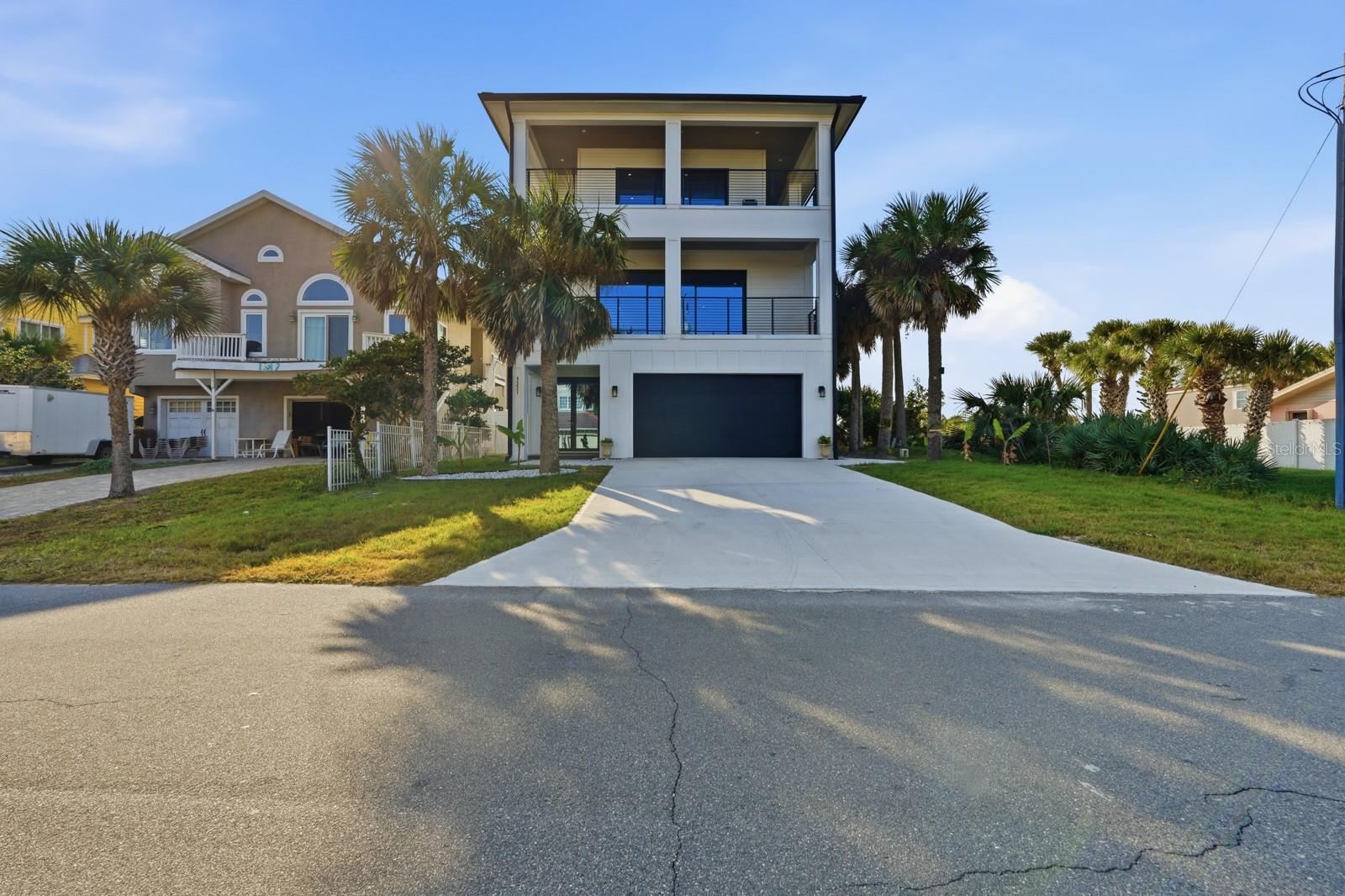 One or more photo(s) has been virtually staged. This stunning three-story coastal retreat blends strength, style, and scenery in perfect harmony. Built with solid concrete block, accented by striking Hardie Plank siding, and topped with a durable metal roof, it offers enduring quality and undeniable curb appeal.
From expansive decks on multiple levels, take in sweeping views of both the ocean and Intracoastal—ideal settings for morning coffee, sunset gatherings, or simply soaking in the coastal breeze. The oversized two-car garage, complete with folding glass doors, doubles as a versatile space for entertaining or extra storage.
Inside, you’ll discover 4 spacious bedrooms and 4 full bathrooms, plus two bonus rooms perfect for a library, office, or creative studio. The thoughtful floor plan provides comfort and privacy, making it ideal for multigenerational living, hosting guests, or enjoying a generous coastal escape.
Set on a prime corner lot just one block from the beach, this home offers convenient access to the shoreline while maintaining a sense of privacy and seclusion. Whether you’re seeking a year-round residence, a vacation getaway, or a smart investment property, this brand-new build delivers the very best of coastal living.  All information is deemed reliable but not guaranteed.