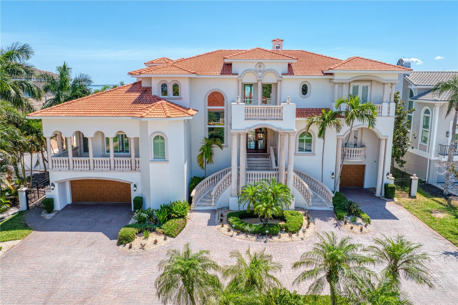 Situated on 100 feet of premier Tampa Bay waterfront, this coastal contemporary estate offers uninterrupted open-water views and a deep-water dock capable of accommodating a substantial yacht.
A set of double doors opens to a light-filled interior defined by soaring ceilings, clean lines, and an elegant flooring. The formal dining room sits to the left, while the main living space unfolds ahead, anchored by a dramatic two-story fireplace and a full wall of glass framing the bay in striking blues.
The living area transitions seamlessly into a refined kitchen featuring a quartzite island, Thermador appliances, and a coastal blue 8-burner gas range, complemented by a well-appointed butler’s pantry. The space opens naturally to the family room, with expansive impact-rated windows and doors maintaining a constant connection to the water.
Oversized balconies extend the living experience outdoors—ideal for entertaining or quiet mornings overlooking the bay as dolphins move along the seawall. The main level also includes a private office, guest suite, and a dedicated lounge with wet bar. Each bedroom is designed with an en-suite bath and generous walk-in closet.
Upstairs, the primary suite opens to a private balcony with views stretching toward the Sunshine Skyway Bridge. Dual walk-in closets and a spacious bath offer a clean foundation for customization. A contemporary bridge overlooks the living area below, connecting the suite while preserving privacy.
A separate guest wing provides two additional suites, a private lounge, and its own balcony—creating a comfortable, self-contained retreat.
An elevator services all levels. In addition to 7,042 square feet of living space, the lower level offers substantial storage, flexible bonus space, and a multi-vehicle garage.
Outdoor living is centered around a lagoon-style pool with spa and waterfall, surrounded by expansive terraces and an outdoor kitchen with bar. A sweeping staircase connects the main-level balcony—complete with fireplace—to the backyard below, creating a natural indoor-outdoor flow.
The deep-water dock, complemented by an updated seawall, features a 10,000-pound boat lift, jet ski lift, and a generous slip.
Located in Tierra Verde, this residence offers a rare balance of privacy and accessibility, just minutes from downtown St. Petersburg, Albert Whitted Airport, and within easy reach of Tampa International Airport.