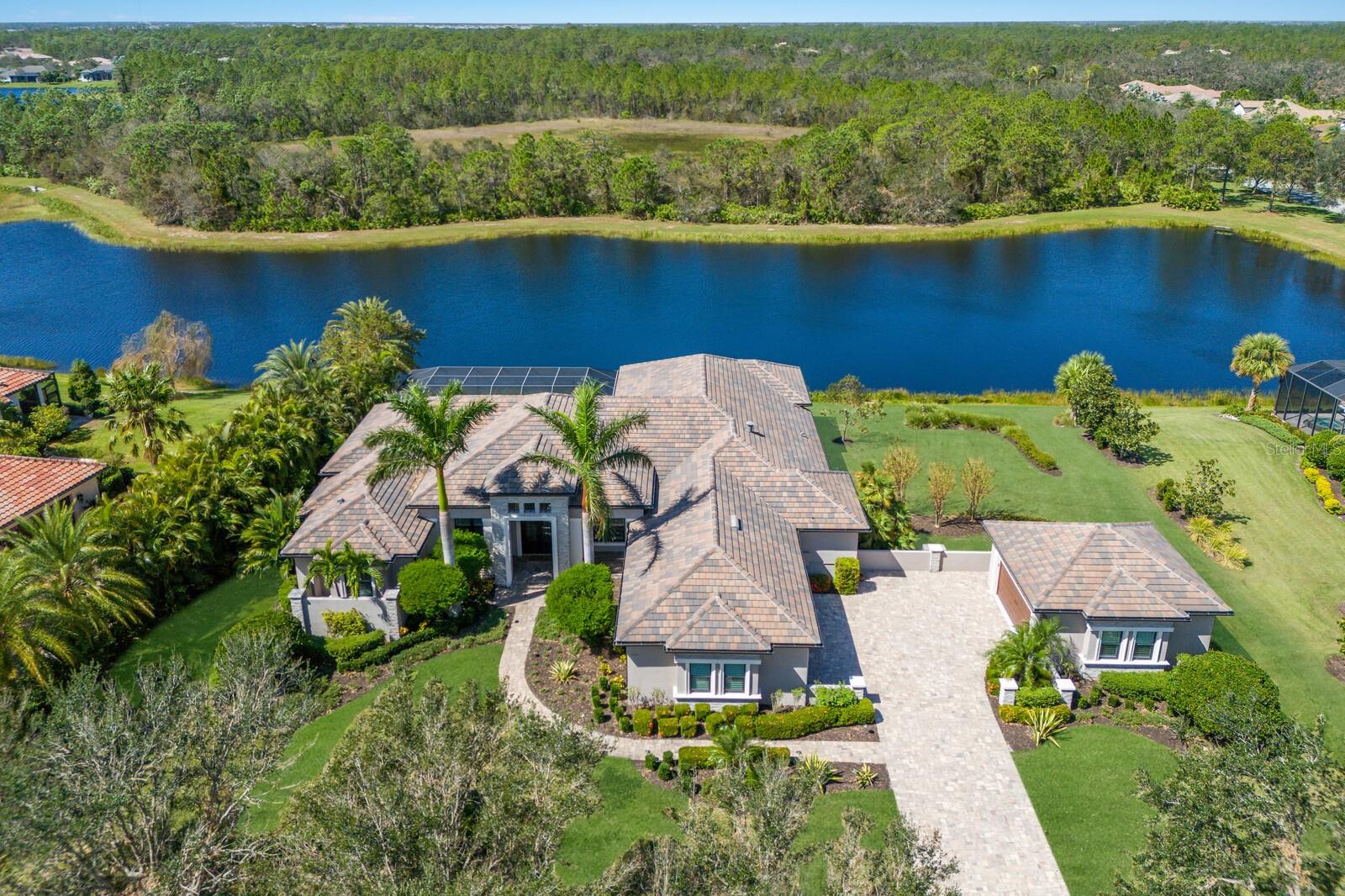 Stellar lake and preserve views on a scenic .70 acre setting in the exclusive and sought-after gated community of The Concession, this four bedroom residence showcases exceptionally planned indoor and outdoor spaces, generously styled detailing throughout, a whole-home GENERATOR, and even a 5 CAR GARAGE. Built 2017, the custom Johnson Homes’ Oakmont plan boasts 4,020 square feet of one-story living and a vastly expansive 1,500+ square feet outdoor living area with abundant open and under cover spaces, pavered deck, full summer kitchen with 2023 grill, PebbleTec heated infinity pool and spa, gas fire table, and a clearview lanai screen. 

Seamlessly connecting this resort-styled lanai to the oversized great room, kitchen, and dining areas are the disappearing 10’ IMPACT GLASS doors into an invitingly open space adorned with large scale 24”x48” porcelain tile, soaring ceilings with designer details, intimate wet bar, built-in wine storage and wine refrigerators, and anchored by the designer feature wall with gas fireplace. Chefs and guests alike will delight in the beautifully appointed kitchen with stainless steel Bosch appliances, sprawling Silestone counters, oversized island, wood cabinetry, dovetail soft-close drawers, herringbone patterned backsplash, and a hidden walk-in pantry. 

Relax and unwind in the grand-sized owner’s retreat positioned on a private wing, offering two walk-in customized closets, double tray ceiling with crown molding, direct lanai access, and a luxuriously appointed spa-like bath with separate vanities, oversized shower and separate soaking tub.  Overnight visitors will be right at home in three additional guest suites, each with walk-in closets, two are ensuite with private full baths, while the third is just off the home’s fourth full bath. Behind double French doors is a voluminous bonus room with stunning coffered ceiling, stone accent wall, and  sliders that open to the lanai.  Additionally the residence offers a spacious study/den off the owner’s retreat via double entry doors adorned with wide plank wood flooring.

Other highlights of this 6,702 total square foot residence includes impact windows/doors/sliders, whole home generator, central vacuum, two tankless water heaters,  solid core interior doors, Crestron smart home system, perfectly sized laundry room with cabinetry and sink, custom built-in bench and cubbies at garage entry, landscape lighting, Eagle textured slate upgraded roof tile, 10’ Mahogany double front doors with 3-point locking system, wood tongue and groove ceilings on front porch and lanai, an oversized attached three-car garage and detached two-car garage with air conditioning unit (both with heavy flake epoxy flooring and insulated impact overhead doors). This captivating residence proudly resides within an exclusive community setting of striking oak hammocks, pines and large lakes, renowned as the home to the World Golf Championship PGA golf tournament in February 2021 and to the World Champions Cup in December 2023, all near dining, shopping, polo, events in the vibrant Lakewood Ranch, Waterside Place, and UTC area, and nearby enough to the enriching culture and beaches of Sarasota.