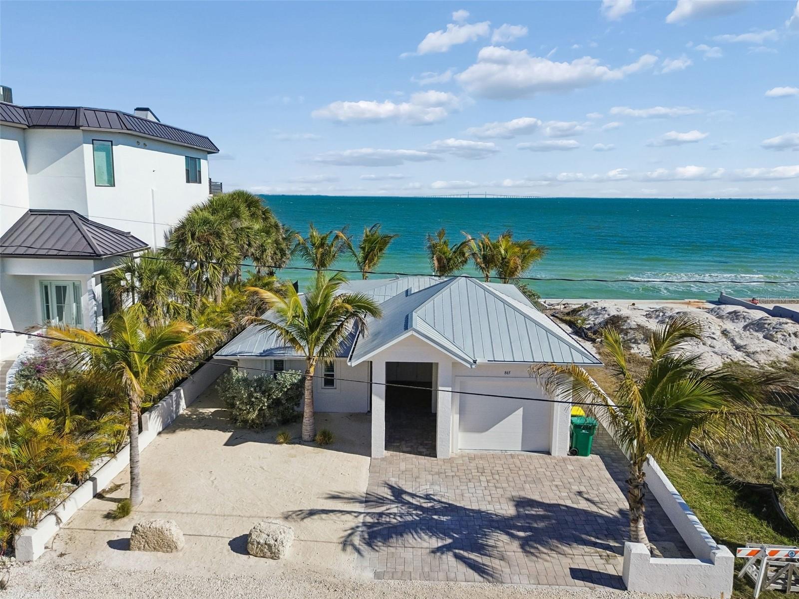 Brand new metal roof! Fully updated, beach front stunner! Situated on the highly coveted north end of Anna Maria Island, this location is unbeatable—just steps from the stunning sunsets and sugary sands of Bean Point, and a short walk to shopping and dining hotspots on Pine Ave. Whether you’re looking for a permanent residence, vacation getaway, or short term rental, this home is move-in ready, can come furnished, and is ready to welcome you to beautiful Anna Maria Island. The open floorplan offers panoramic views of Tampa Bay from the kitchen, dining and living rooms ideal for watching wildlife, sailboats, and the twinkling lights of the Skyway Bridge. The kitchen is newly renovated with brand new appliances, cabinetry and counter tops. Additional updates include roof (2026), AC (2025), water heater (2025), new interior paint (2025), updated lighting and hardware, newly reinforced seawall. The sandy backyard with a new patio, is the perfect beach hangout spot to grill, relax, and even cast a line and fish from your own backyard. Designed for beach living, this island home includes ample storage for all your gear, including a large laundry room, multiple storage closets, and a detached 1-car garage—perfect for your beach essentials, island golf cart, and bikes. This beachfront gem offers everything you need to embrace the ultimate Anna Maria Island lifestyle.