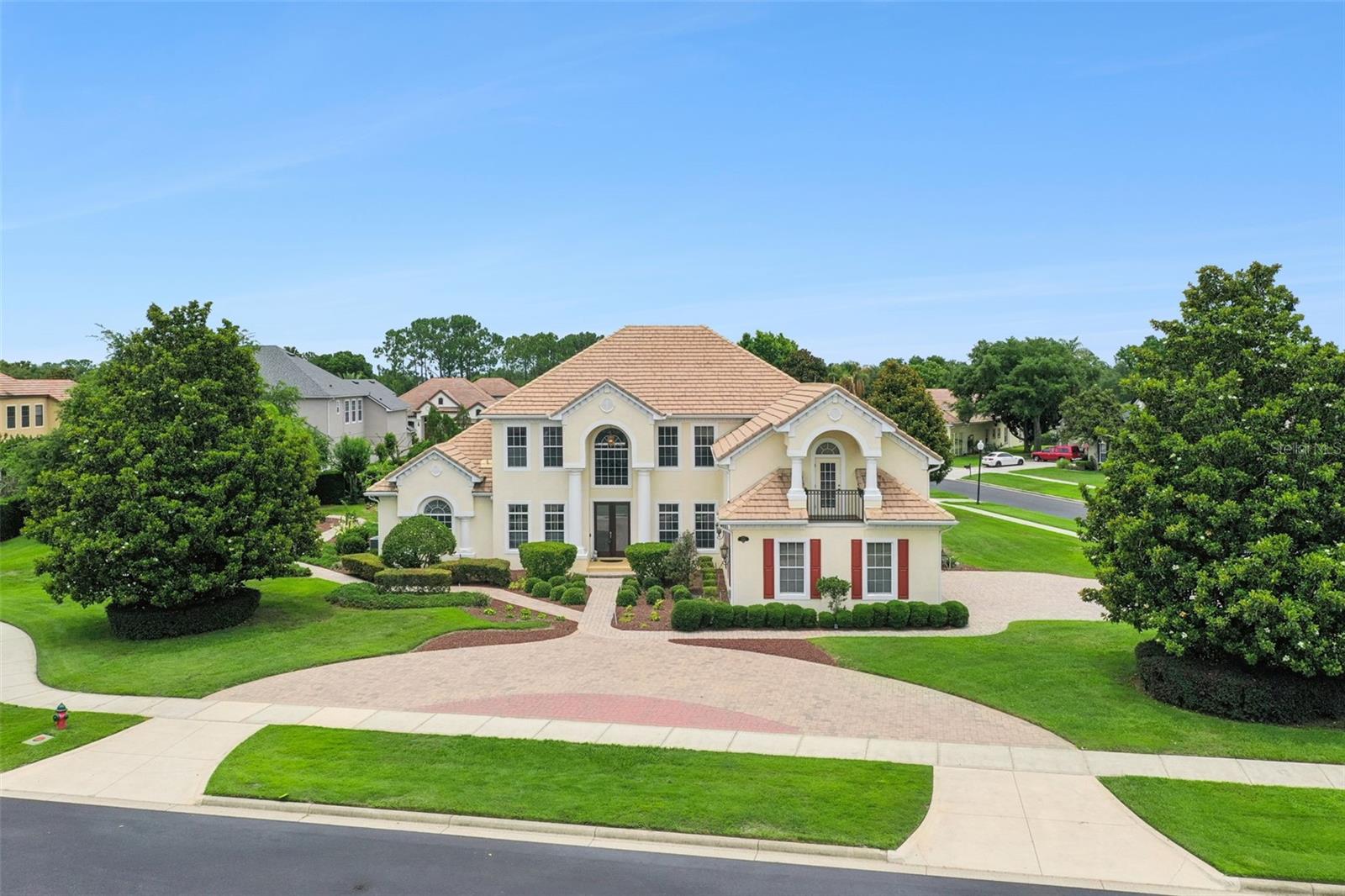Live the life you deserve in this extraordinary custom residence on the largest homesite within the guard gated Legends Golf & Country Club. Combining timeless elegance with exceptional craftsmanship, this remarkable four-bedroom, 5.5-bath estate offers an unparalleled blend of luxury, comfort and privacy. A beautiful tiled roof, newly installed paver circular driveway and side entry three car garage create an impressive first impression. Enter through the grand leaded glass double entry doors and into a breathtaking interior where soaring two story ceilings, exquisite architectural details, crown molding, custom finishes and stunning views of the pool set the tone for the home that awaits. Designed for grand entertaining and everyday living, the expansive floor plan features a dramatic living room with fireplace, an elegant formal dining room, a private office behind French doors and a spacious gourmet kitchen that will delight any chef. Rich cabinetry, granite countertops, a large center island, stainless steel appliances, built in cooktop, decorative backsplash, generous dining area and an oversized hidden walk in pantry provide beauty and functionality. The luxurious primary suite occupies its private wing on the first floor. Featuring rich wood flooring, tray ceilings, French doors leading to the lanai, a convenient wet bar, dual walk in closets including a custom California Closet system, and a spa inspired bath with a center soaking tub, oversized walk through shower, dual vanities and granite counters, this retreat offers the ideal place to unwind. Upstairs, family and guests will enjoy exceptional flexibility with three additional bedrooms, including a private en suite, a spacious loft, and a dedicated home theater room complete with projector, screen and prewired surround sound. A full bath adjacent to the theater creates the potential for a private guest or multigenerational living area. Outdoor living is where this home shines. The private screened pool and heated spa area have been thoughtfully designed for entertaining on any scale. An expansive paver deck surrounds the sparkling pool, while the covered lanai features a summer kitchen complete with built in grill and sink, creating the ideal setting for weekend gatherings, holiday celebrations or quiet evenings under the stars. Mature landscaping and thoughtful placement provide exceptional privacy rarely found in community living. One of the home's unique features is the beautifully landscaped garden along the side of the property. Shaded by mature greenery and designed as a peaceful retreat, it offers an ideal setting for morning visits, yoga, meditation, reading or simply enjoying the tranquility of your surroundings. Residents of Legends enjoy a resort-inspired lifestyle with 24-hour guarded entry, championship golf, tennis courts, community pool, fitness and recreation facilities, and a vibrant social atmosphere, all conveniently near shopping, dining, healthcare and major roadways. This is more than a home. It is a private sanctuary designed for those who appreciate luxury, space and the finer things in life.